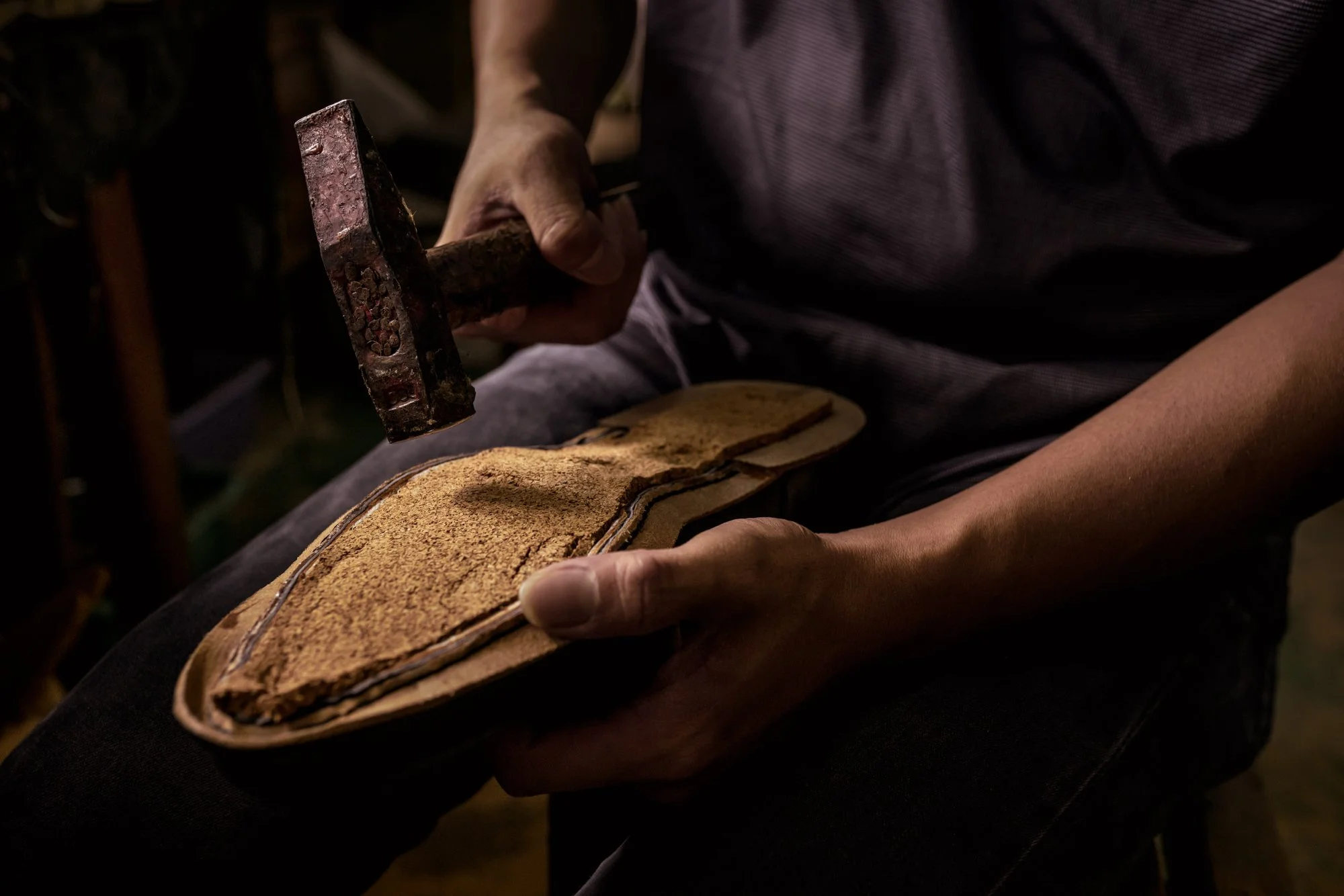  A sticky mass of crushed cork is smeared into the hollow space under the insole of shoe using a hammer by worker at Prime Shoes factory. 