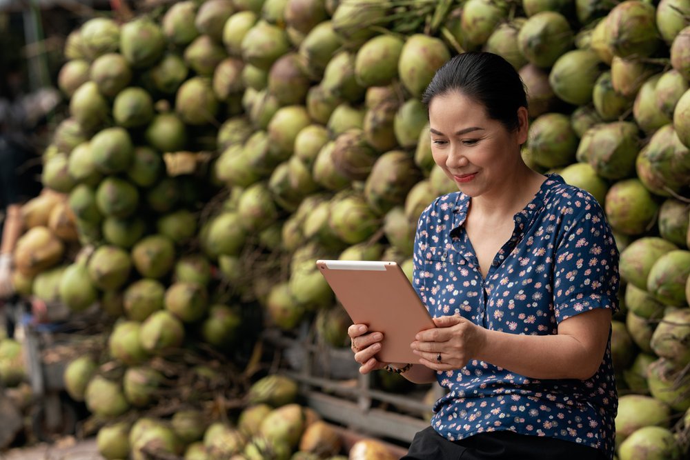  Market seller checking sales on iPad at her   cocunut stall in wholesale market. 