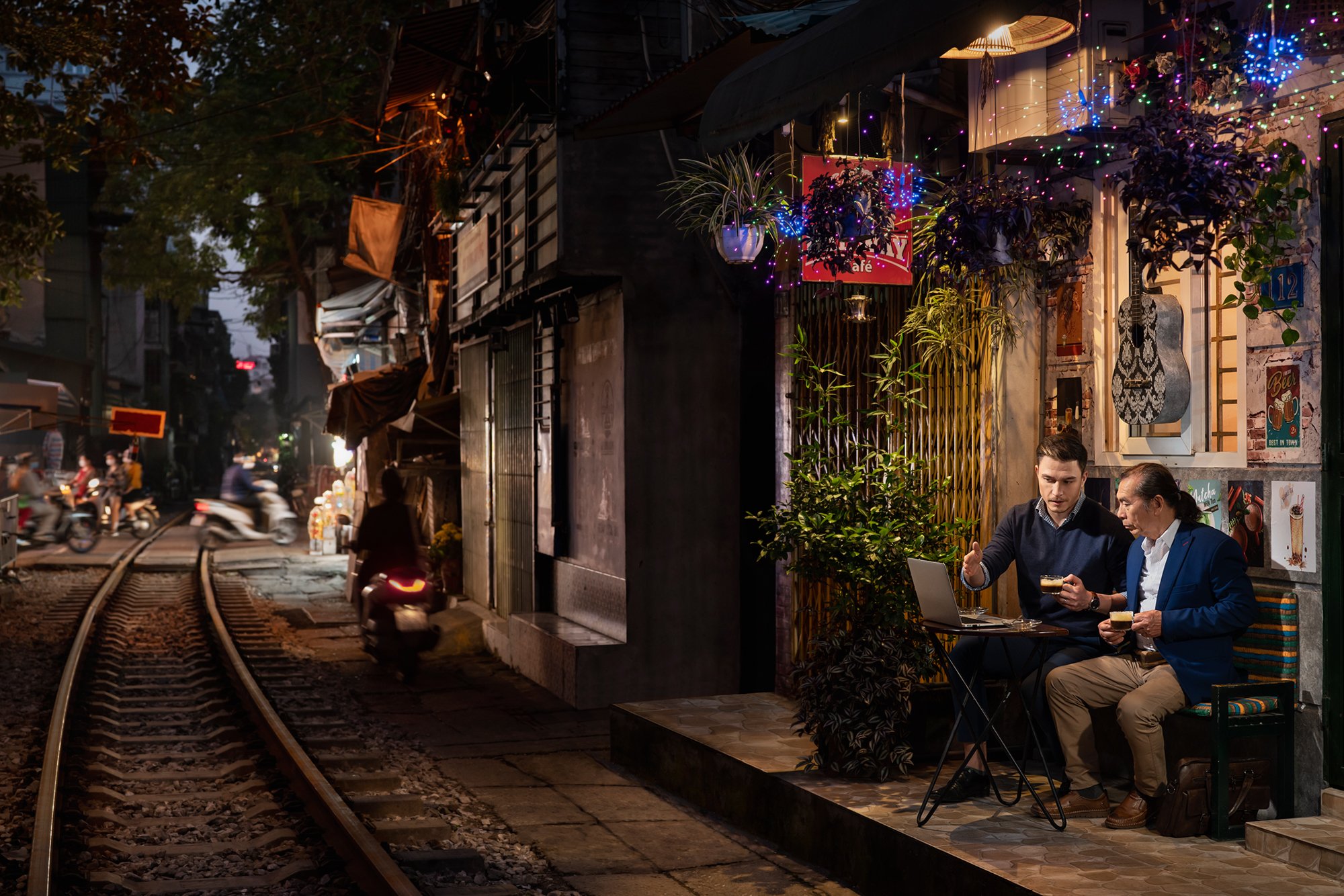  Western entrepreneur and Vietnamese businessman chat business at Hanoi Train Street coffee shop. 
