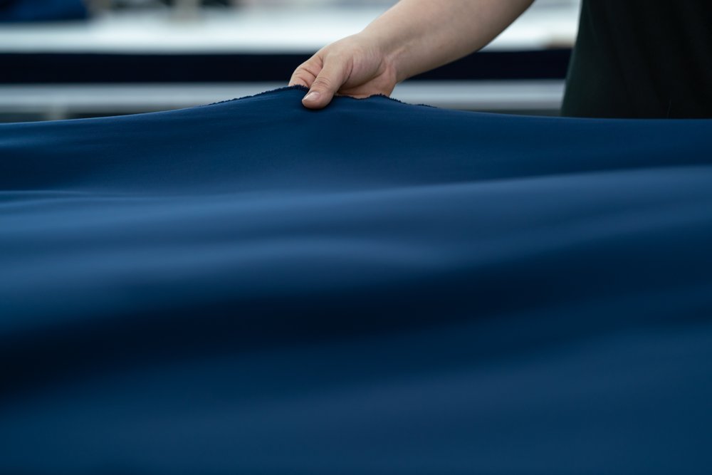 Detail of hand holding fabric as it is measured in textile factory.