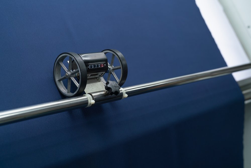 Navy fabric roll is rolled through machine and to measure length  of roll.