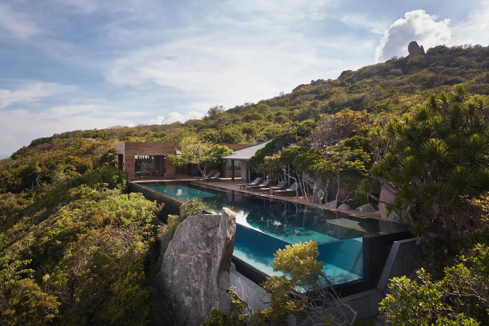  Amanoi Ocean Pool Residence infinity pool overlooking the ocean, surrounded by lush forest and expansive decking. 