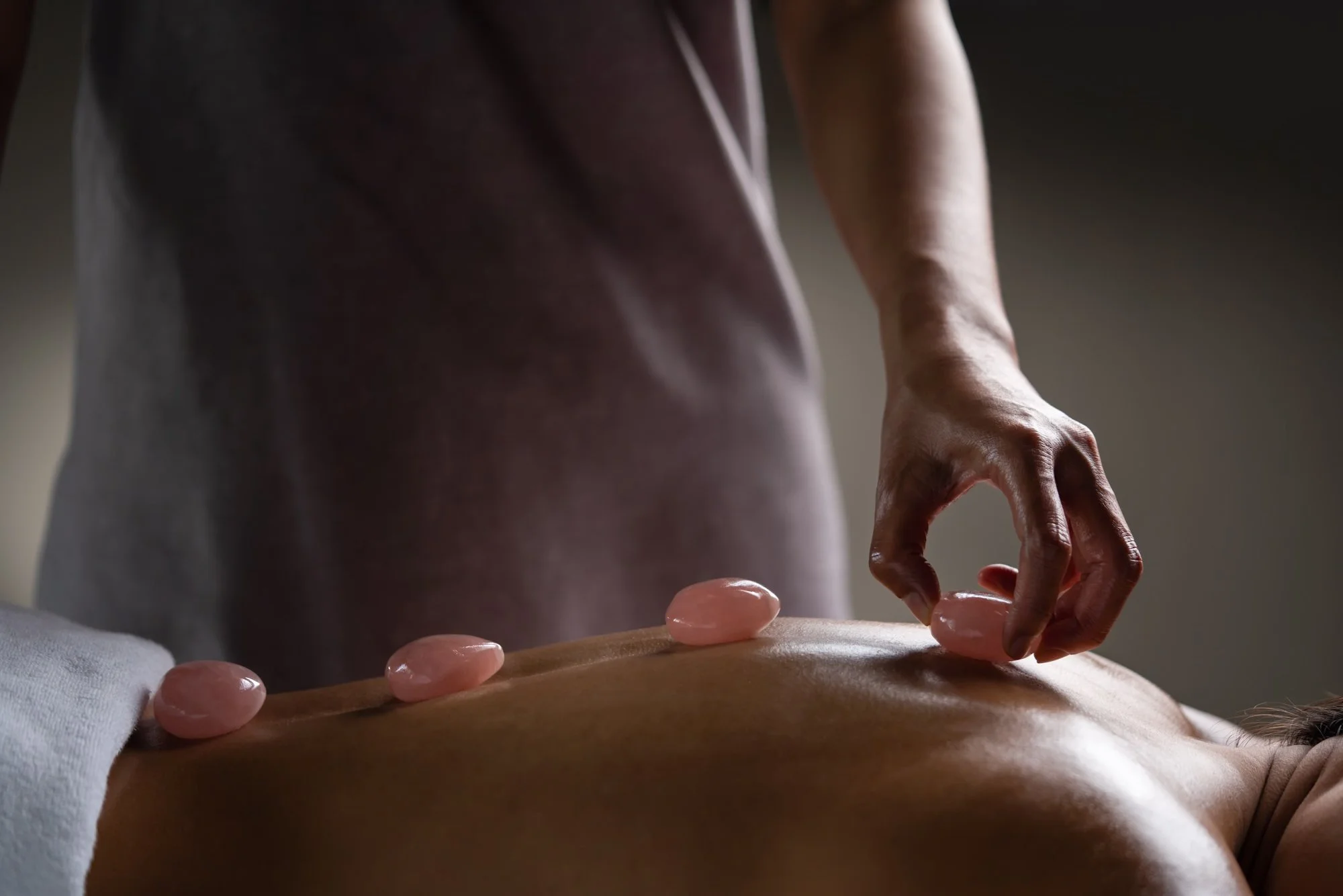  Hot stone massage treatment at Amanoi, with rose quartz stones placed along the back during a relaxing spa treatment. 