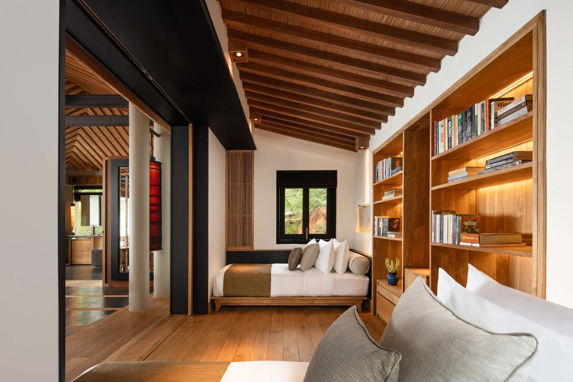  Amanoi Residence children’s bedroom with twin beds, built-in wooden bookshelves and an exposed timber-beamed ceiling overlooking the surrounding forest. 