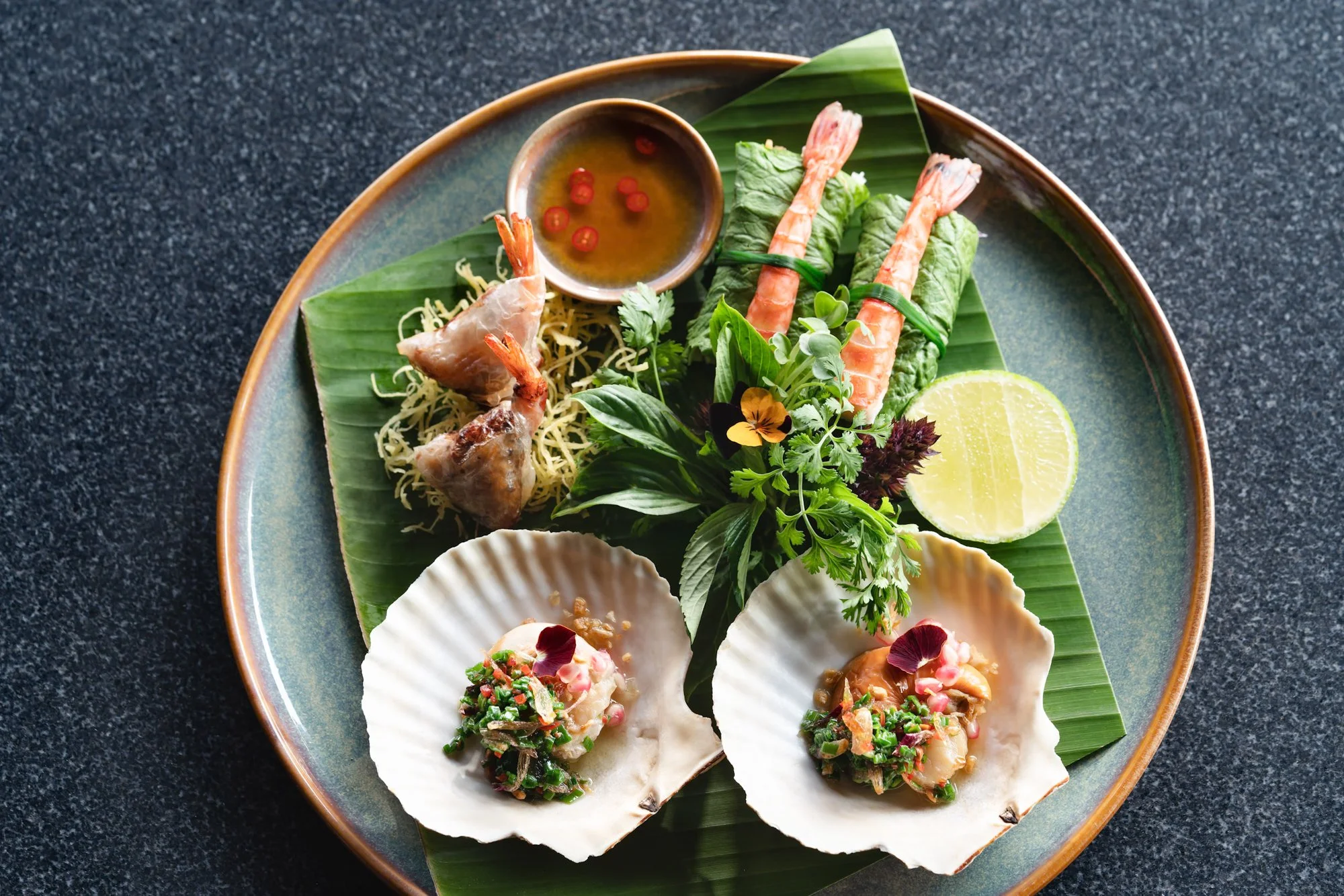  Amanoi Vietnamese cuisine featuring fresh shrimp rolls, grilled prawns and scallop dishes served with herbs, lime and dipping sauce on a banana leaf. 
