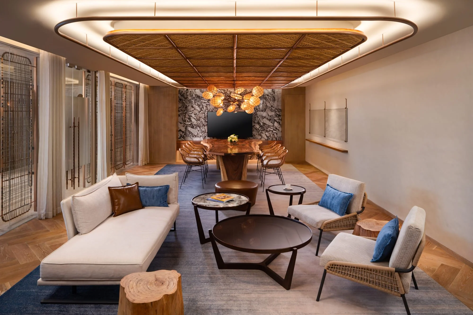  The Square at New World Hoiana Beach Resort, featuring a contemporary lounge and dining area with rattan furnishings, a sculptural timber dining table and warm ambient lighting. 