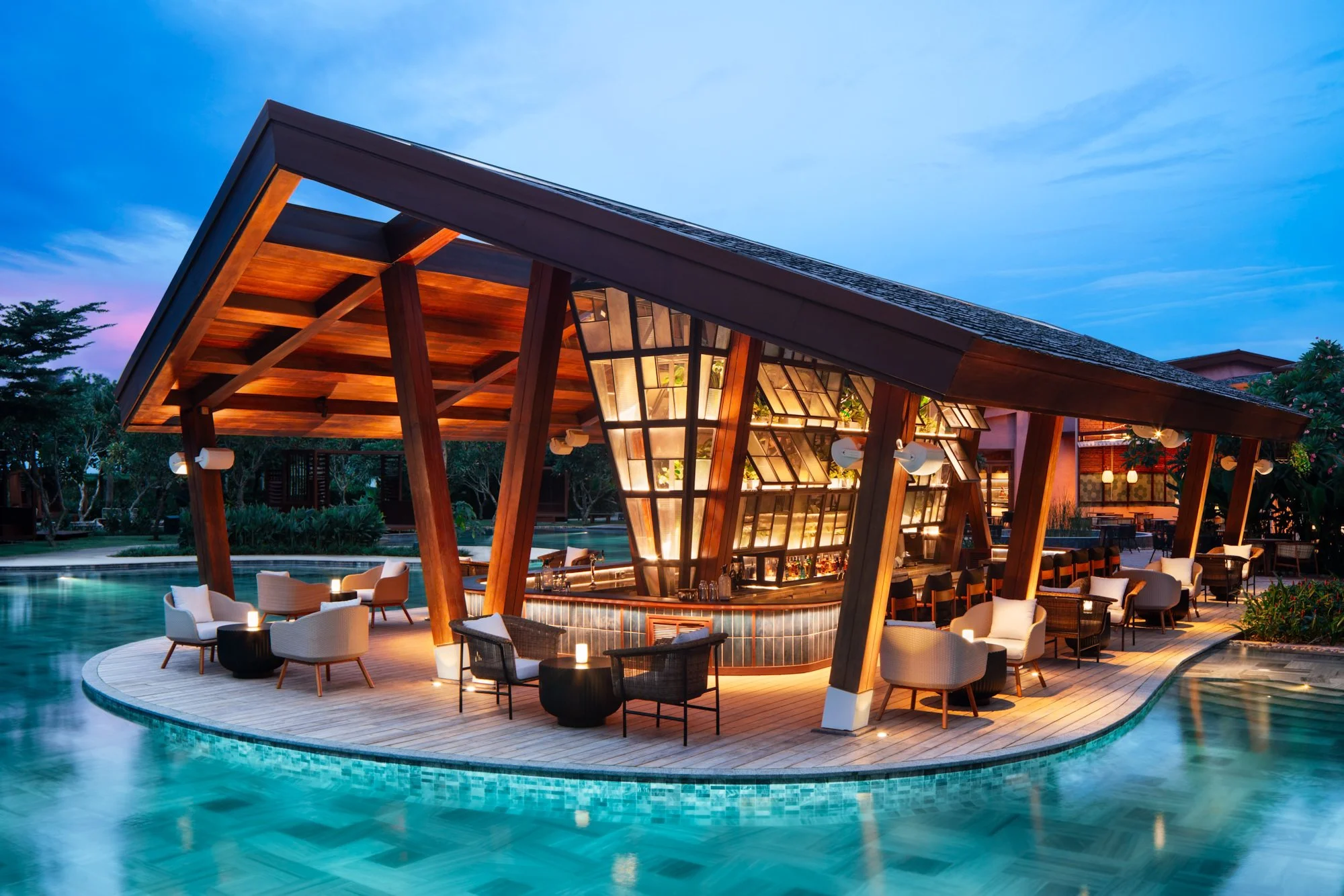  NOX Beach Club poolside bar and lounge at dusk, featuring a timber pavilion, central bar, outdoor seating and a swimming pool surrounding the terrace. 