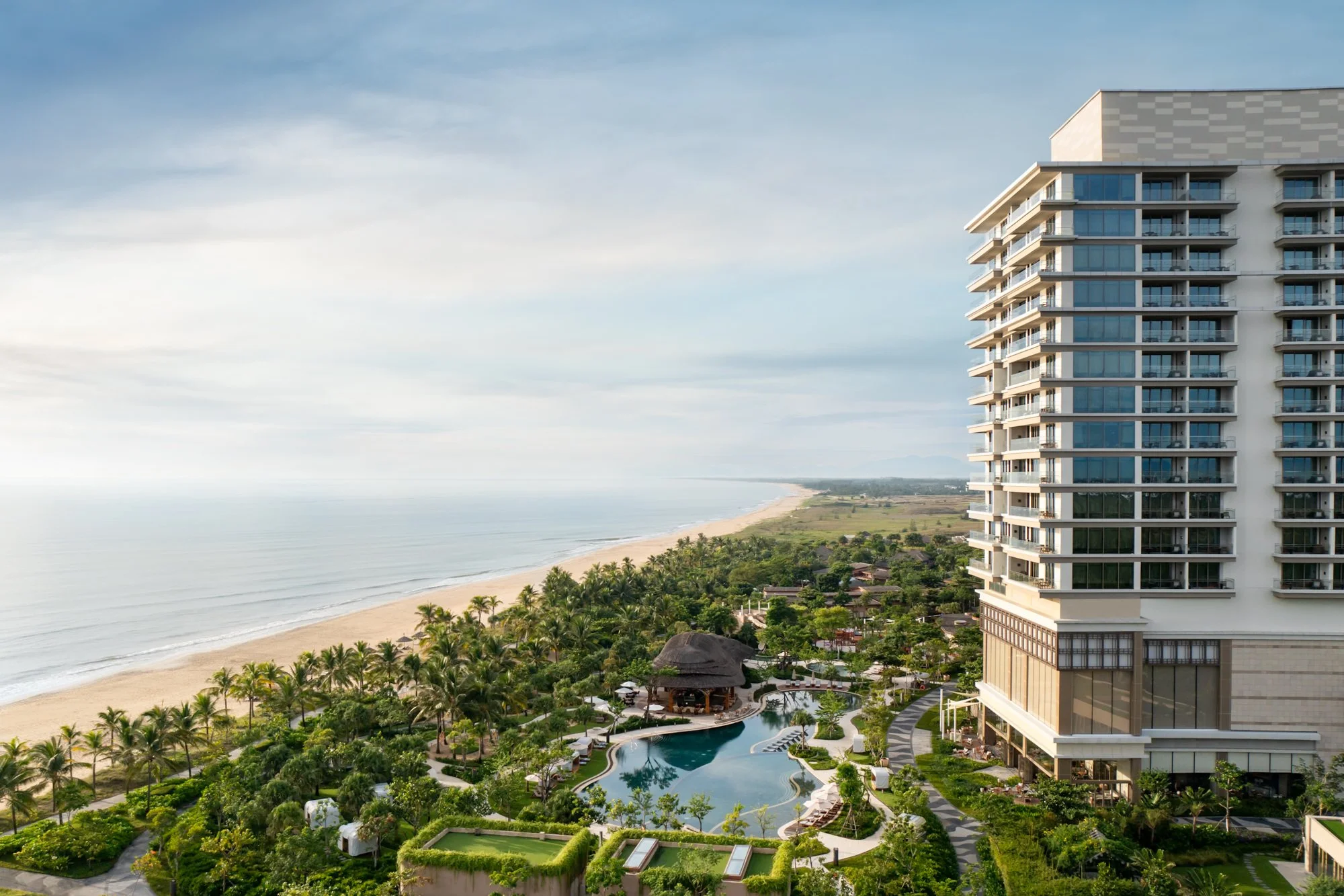  New World Hoiana Beach Resort overlooking the long sandy beach, with the resort’s landscaped gardens, swimming pool and oceanfront setting. 