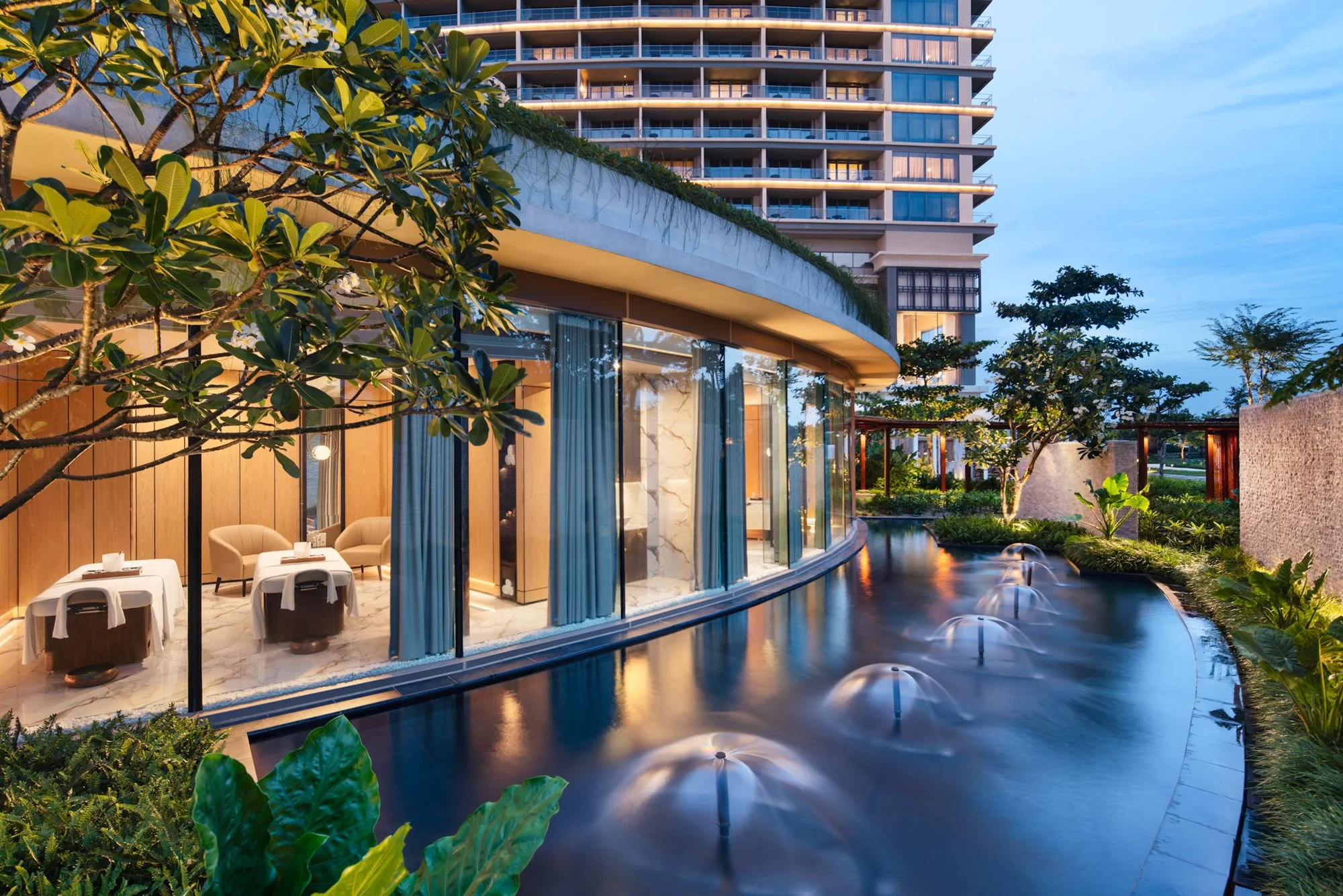  Downtime Renew Spa at New World Hoiana Beach Resort, with treatment rooms overlooking a tranquil water feature and lush tropical gardens. 