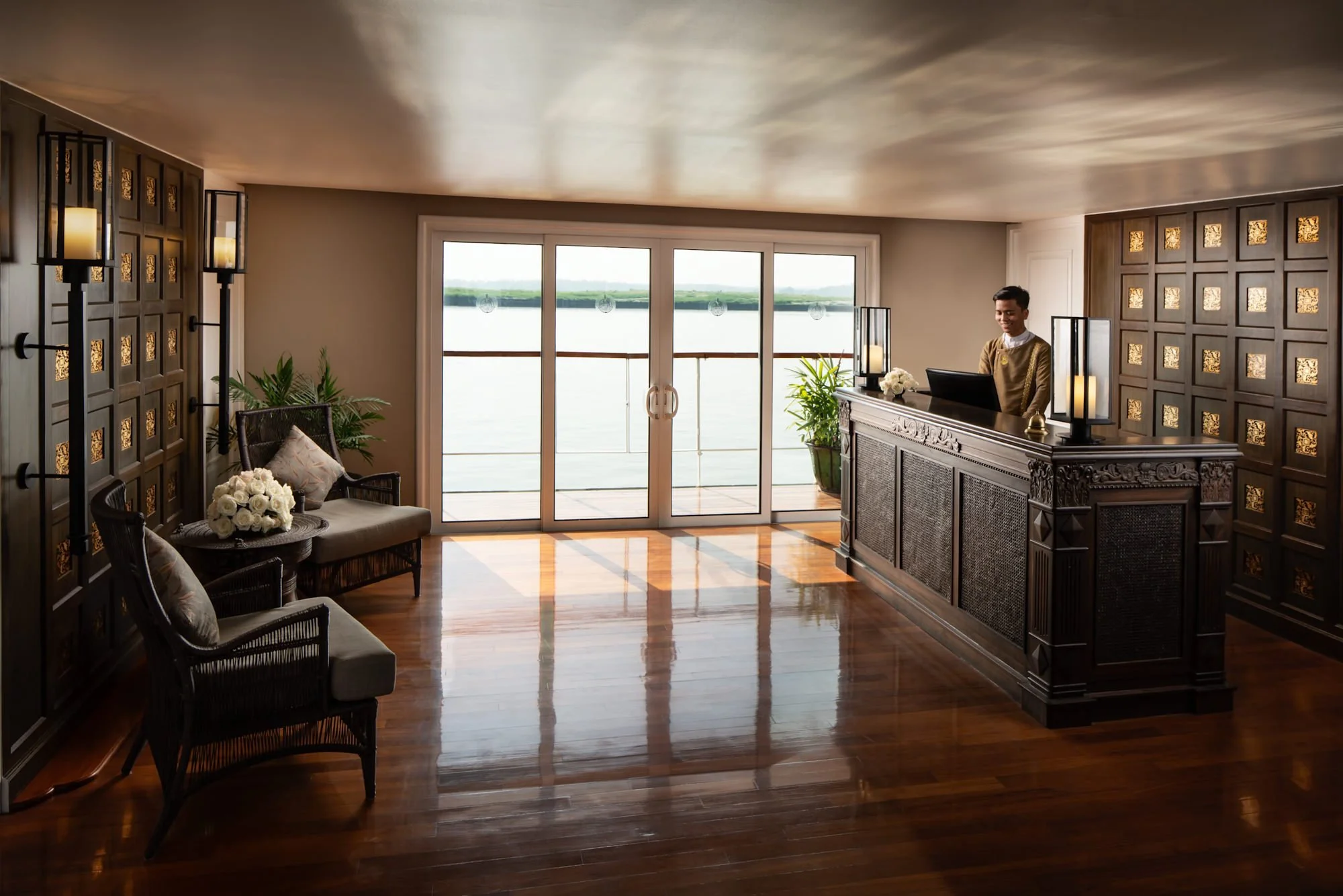  Reception aboard The Strand Cruise on the Irrawaddy River in Myanmar, featuring a traditional Burmese-inspired reception desk, elegant lounge seating and views of the river. 