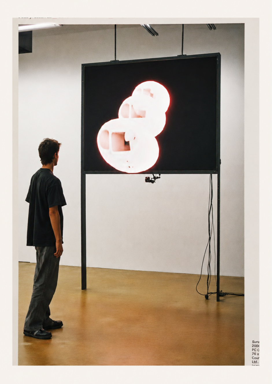 A gallery visitor stands in front of a large screen displaying bright abstract forms generated through real-time video analysis.