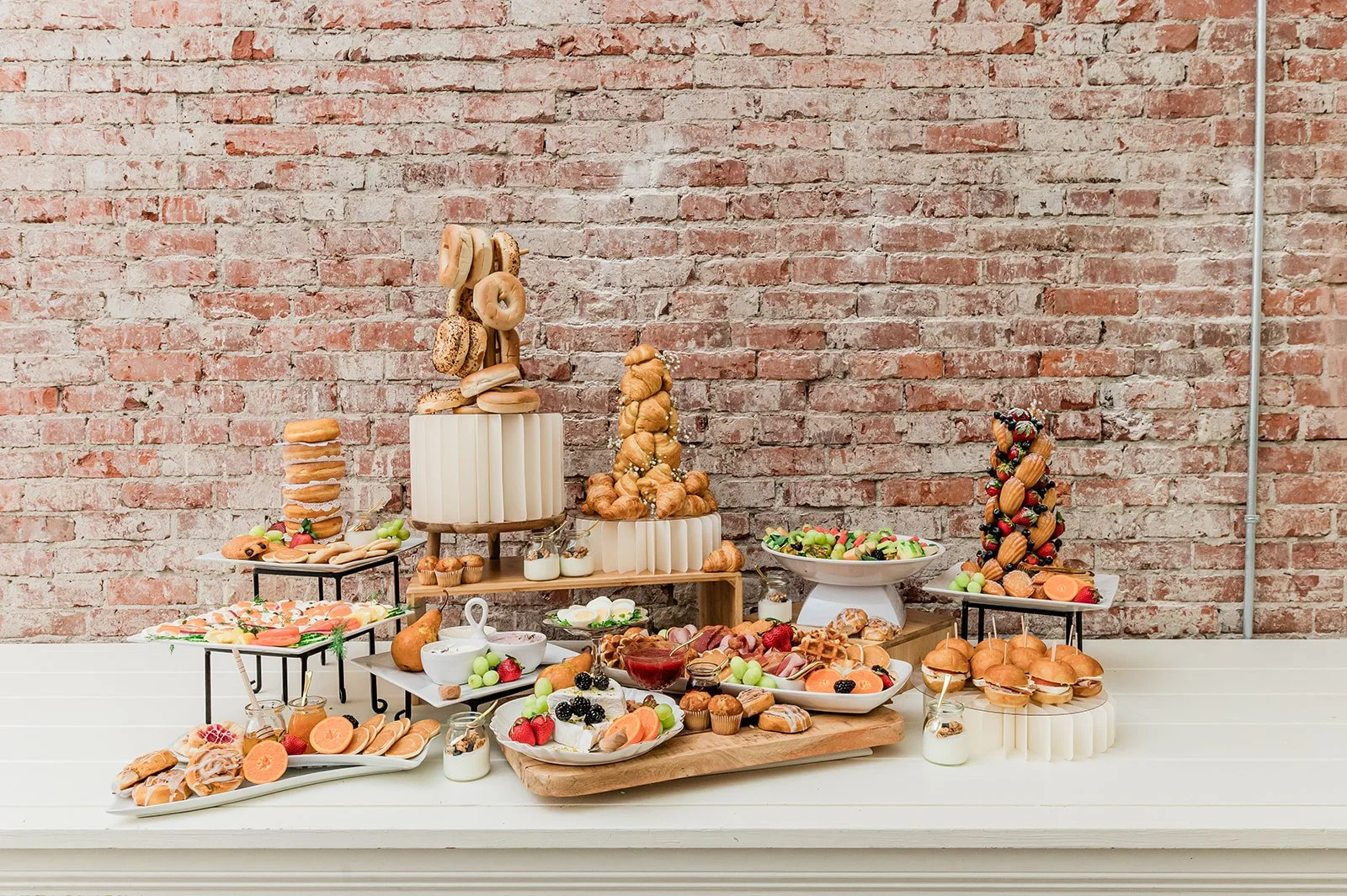 Post-wedding brunch spread at The Velvet & Oak — full brunch charcuterie table against original brick, bagel tower, croissants, fruit