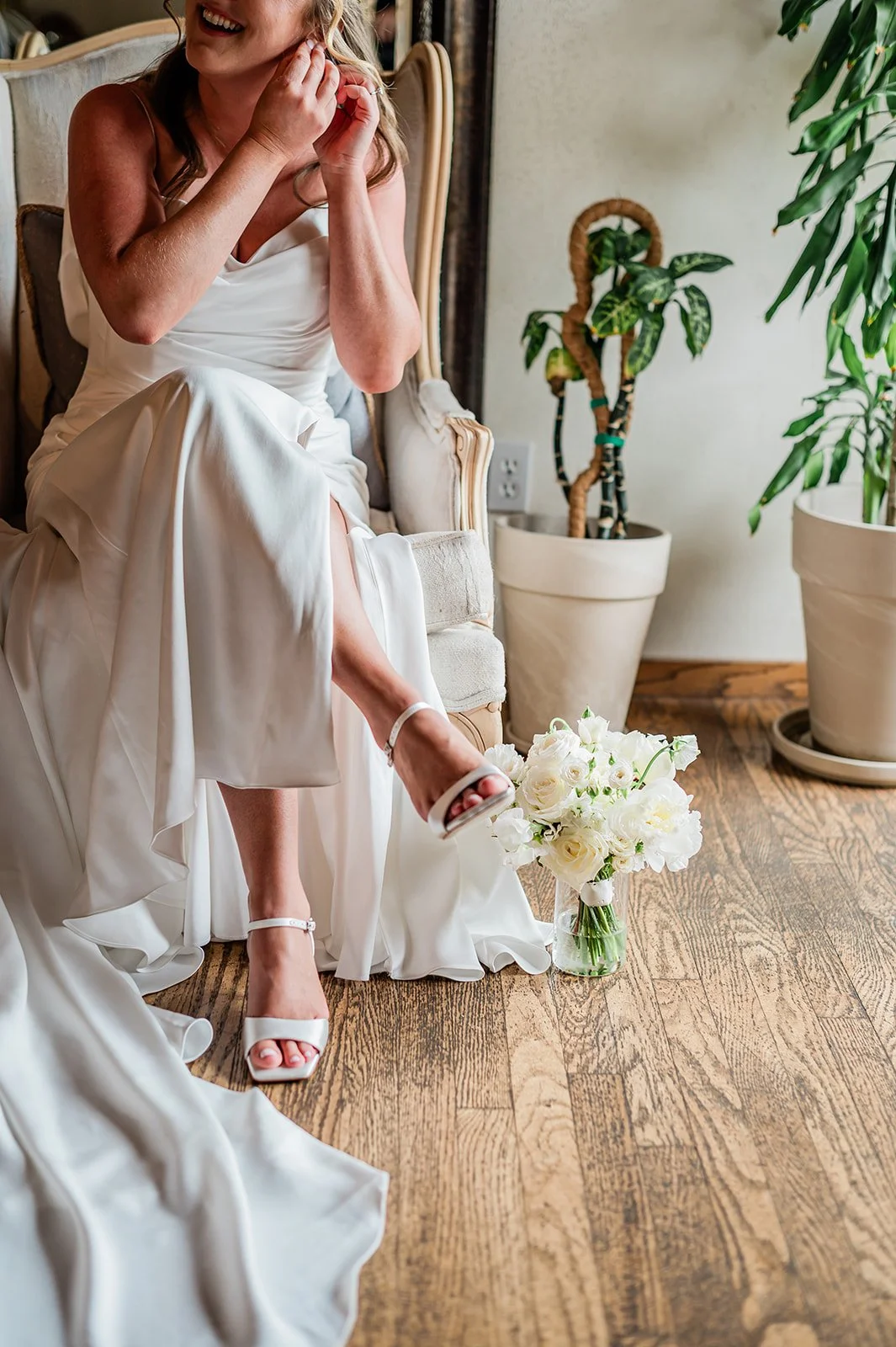 Bride putting on her earrings in the sunlit getting-ready suite at Chateau Lill