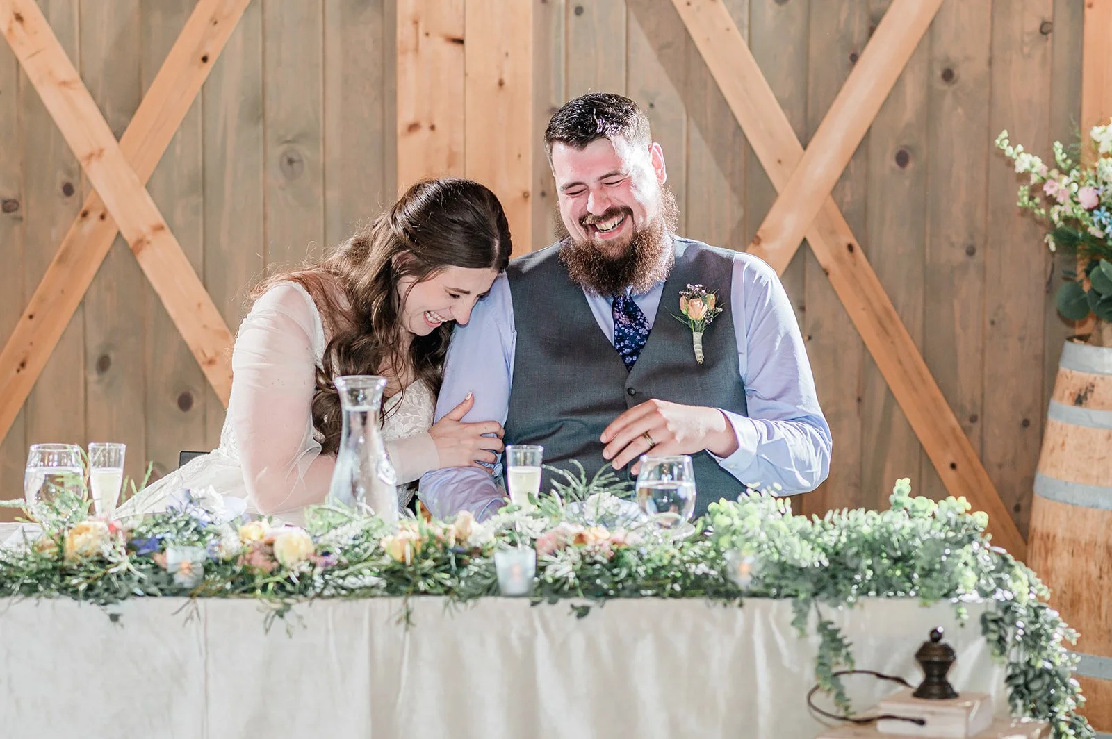 Newlyweds laughing together at their sweetheart table during wedding toasts