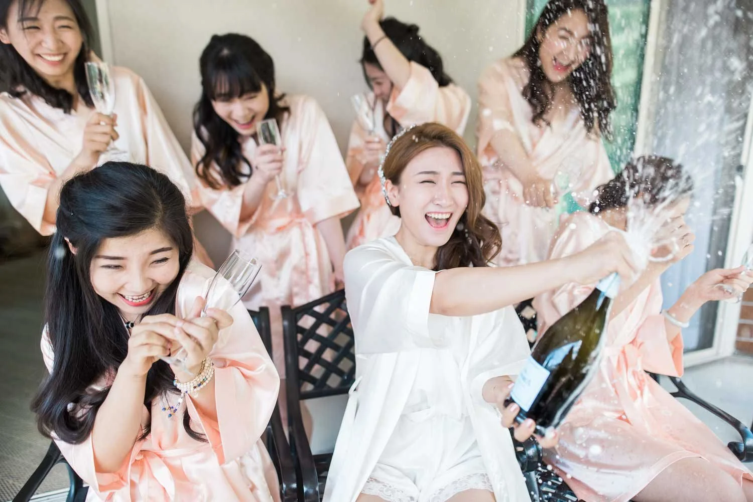 Bridesmaids celebrating with champagne during getting-ready photos