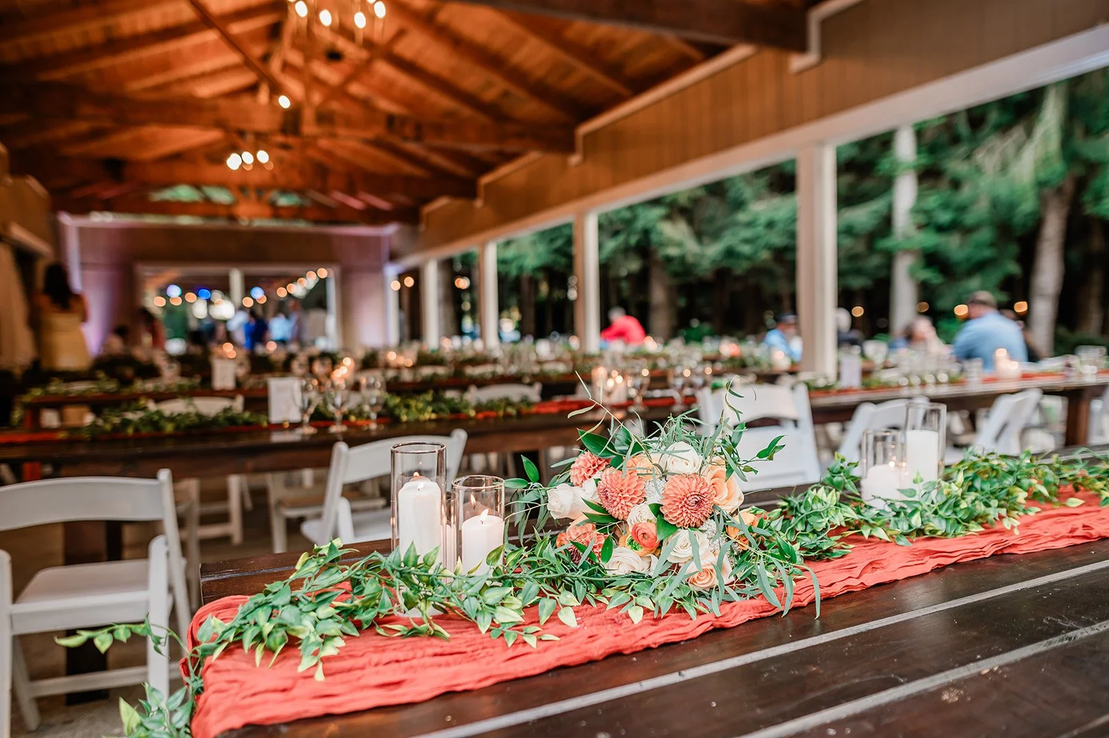  Reception tables with terracotta runners and orange florals under the pavilion at Woodland Meadow Farms 