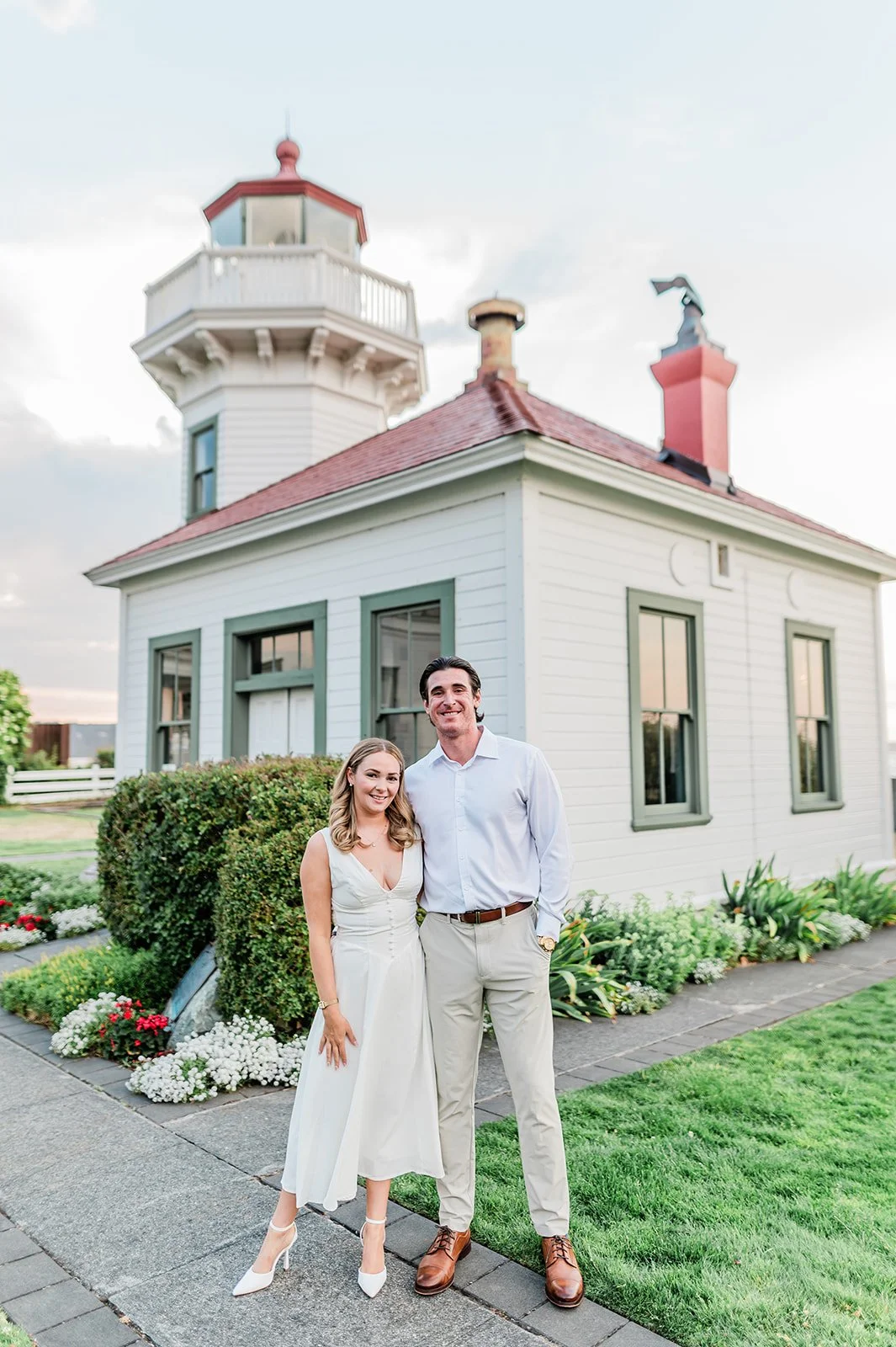 Couple standing in front of Mukilteo Lighthouse in white dress and blazer
