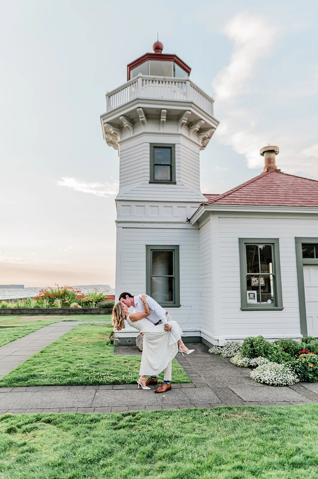 Couple dip kiss on the lawn beside Mukilteo Lighthouse