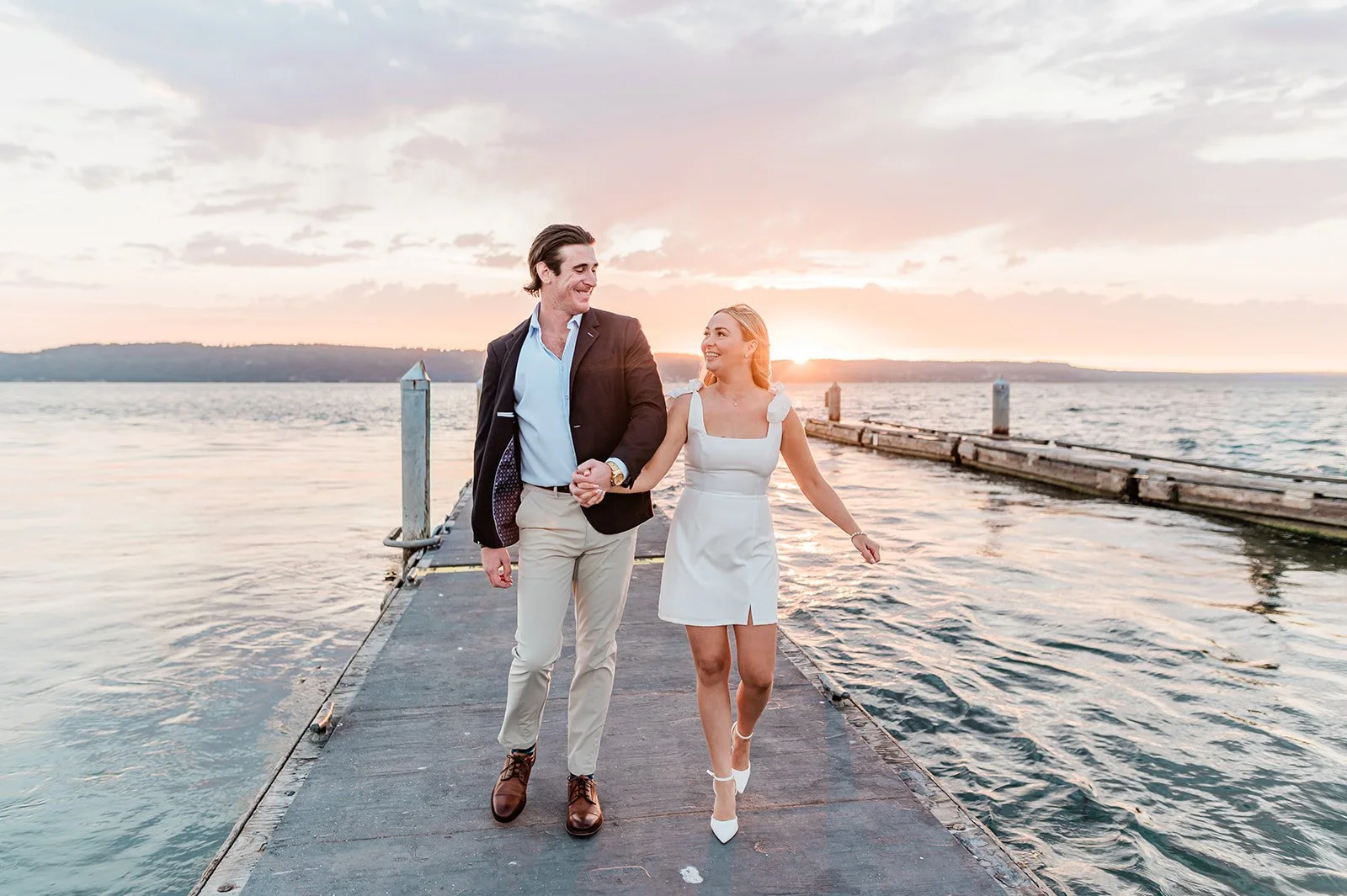 Couple walking hand in hand down the Mukilteo dock at sunset