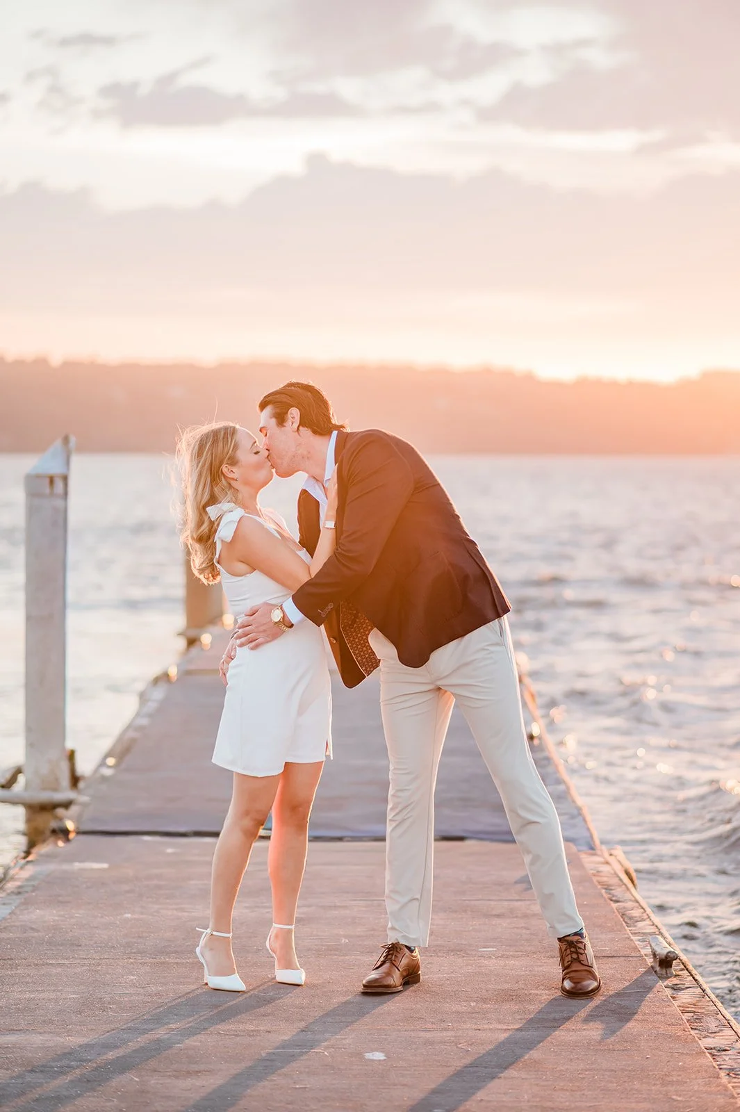 Couple kissing on a windy dock at sunset in Mukilteo