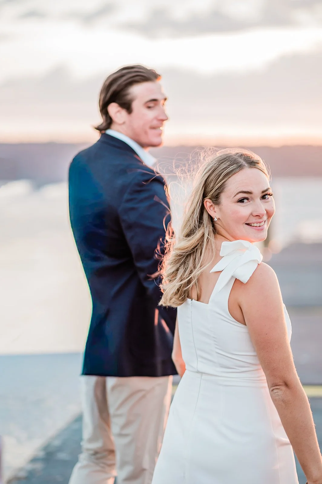 Fiancée looking over her shoulder in a little white dress with tie shoulders