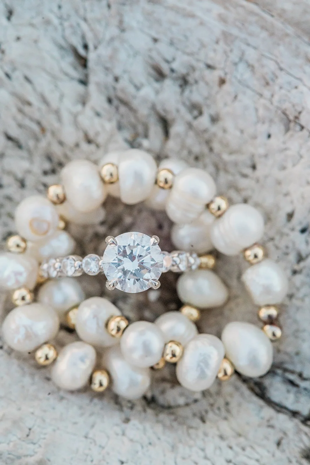 Diamond engagement ring resting on a pearl bracelet