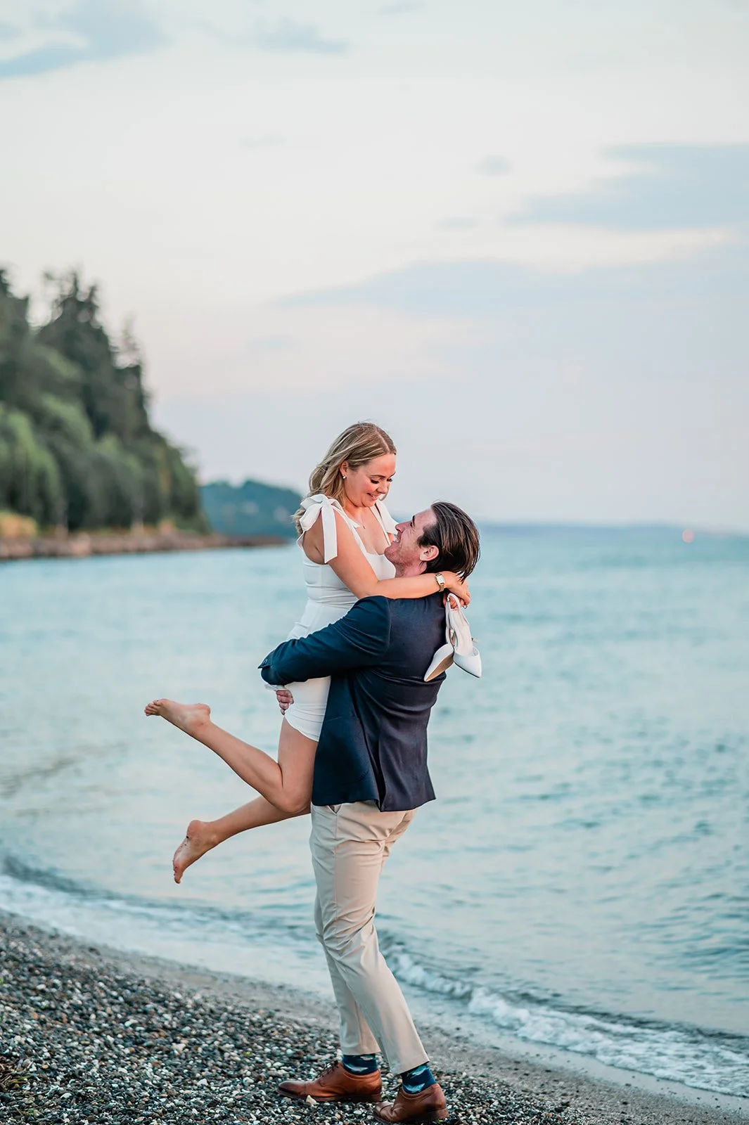 Fiancé lifting fiancée into the air on the beach in Mukilteo