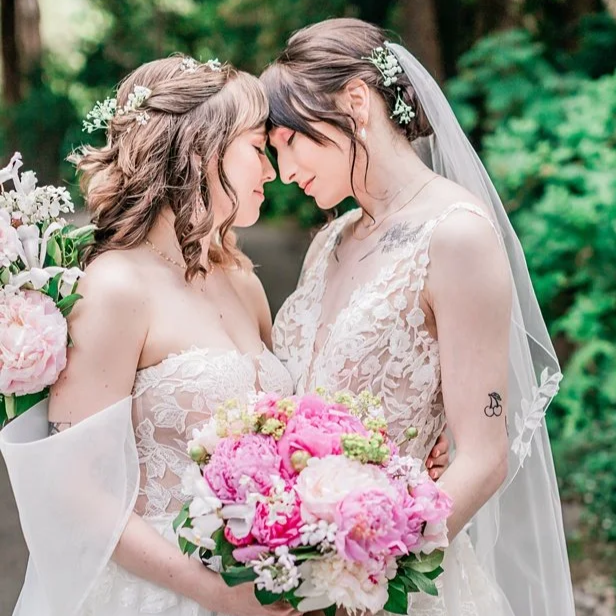 Two brides sharing a first look moment with pink bouquet