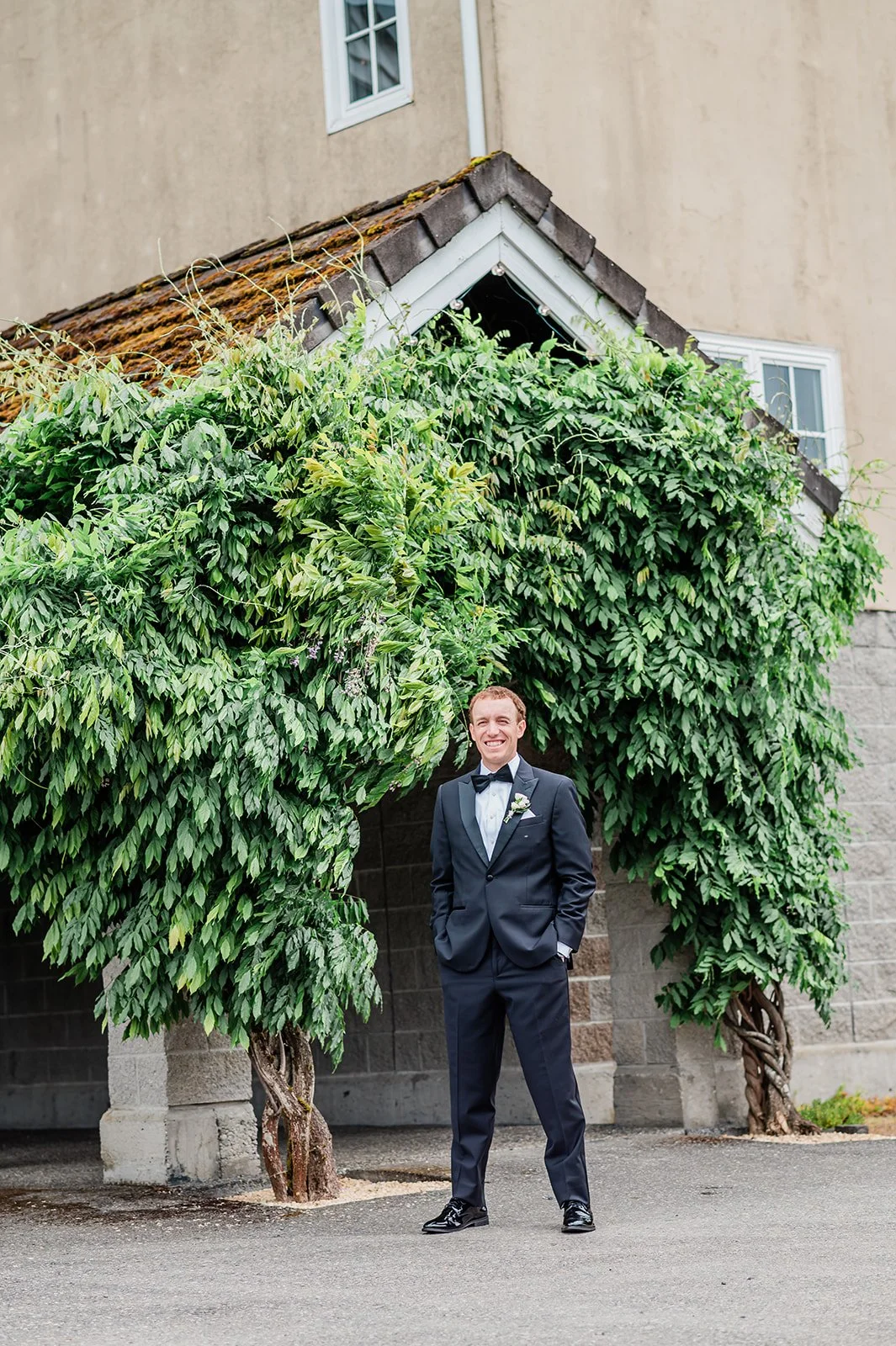 Groom waiting under the wisteria-covered entrance at Chateau Lill before the first look