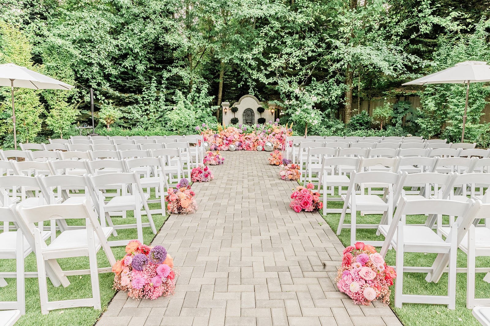 Jackson Manor ceremony aisle lined with pink and coral florals leading to a stone alcove backdrop