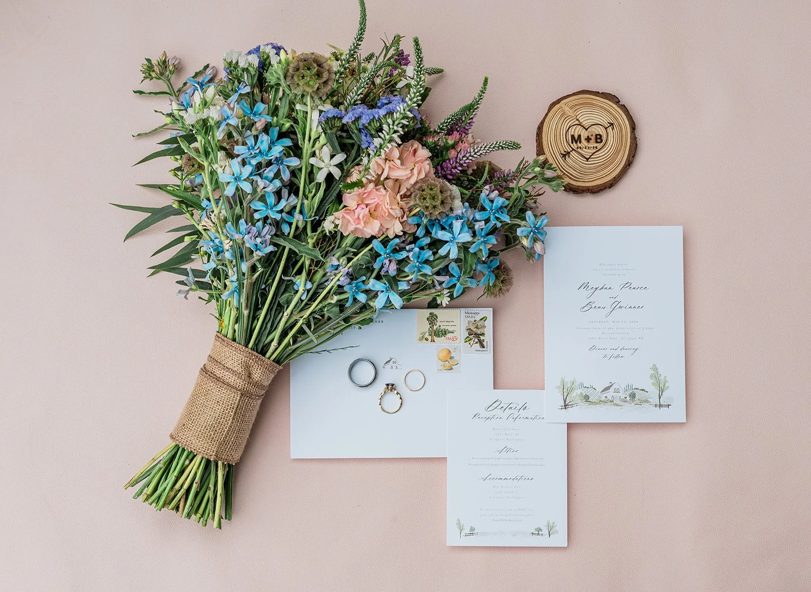 Wildflower bouquet with wedding invitation and wood ring box on a blush background