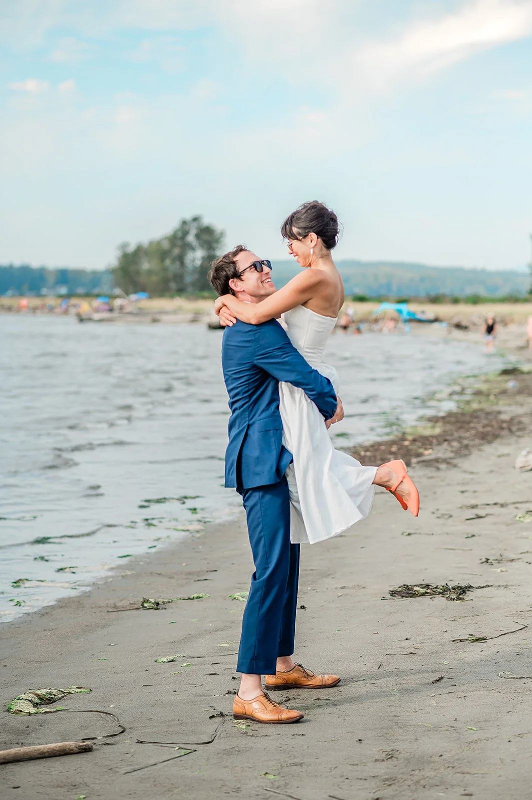 Jetty Island wedding photographer captures groom lifting bride on the beach in Everett Washington with Salish Sea in the background