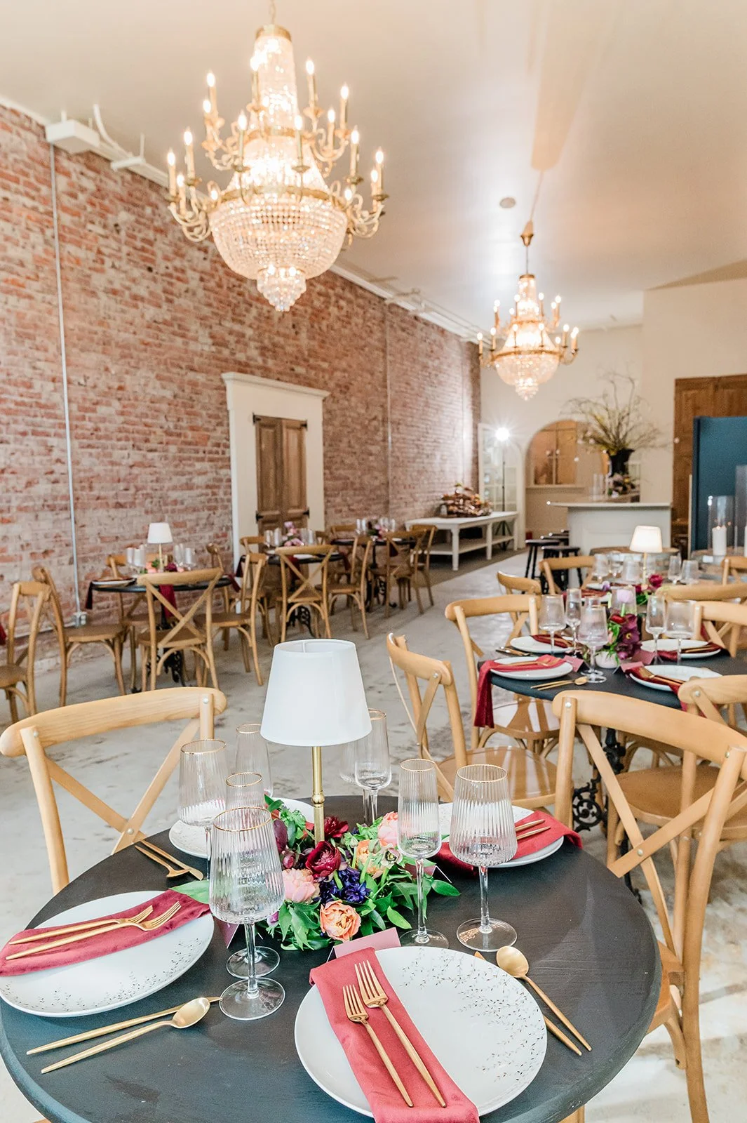The Velvet & Oak rehearsal dinner setup — moody jewel tones, round tables, European chandeliers