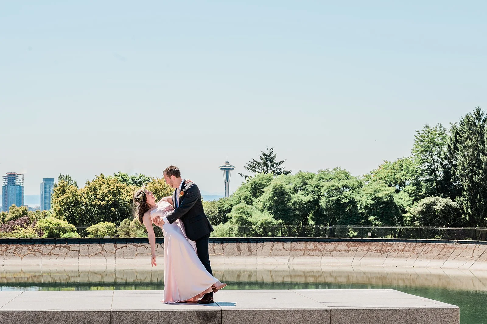 Groom dipping bride with the Seattle skyline in the background at Volunteer Park