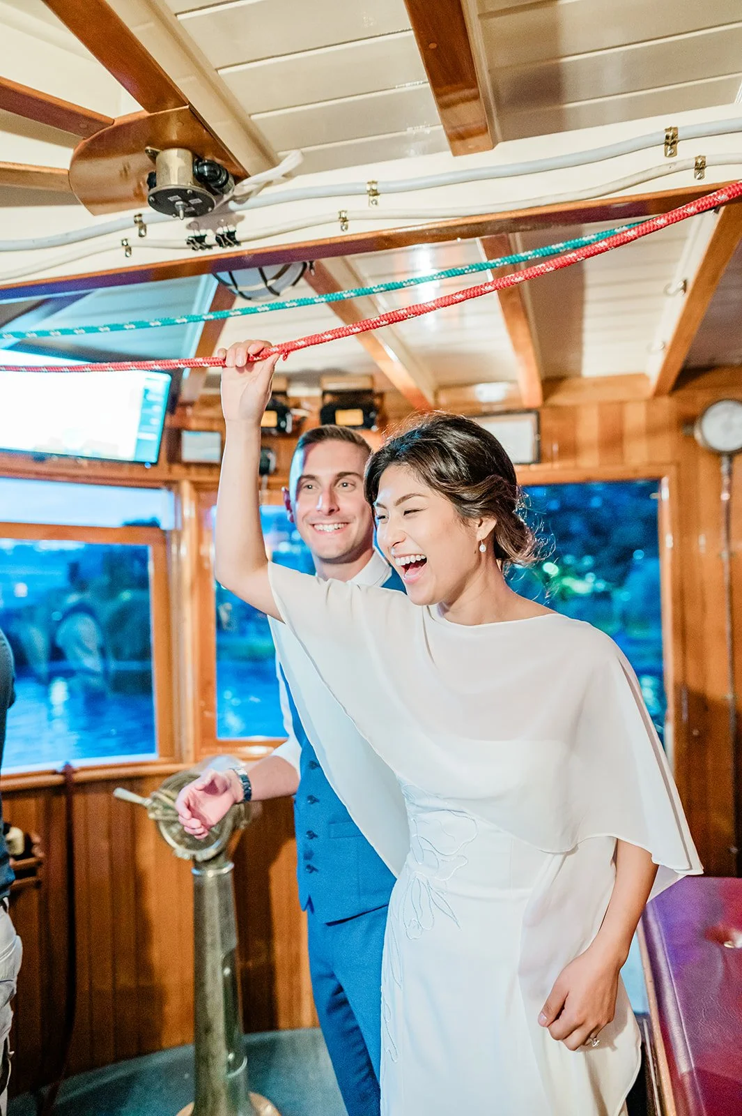 Bride laughing at the captain's wheel during her Seattle boat wedding, virginia V
