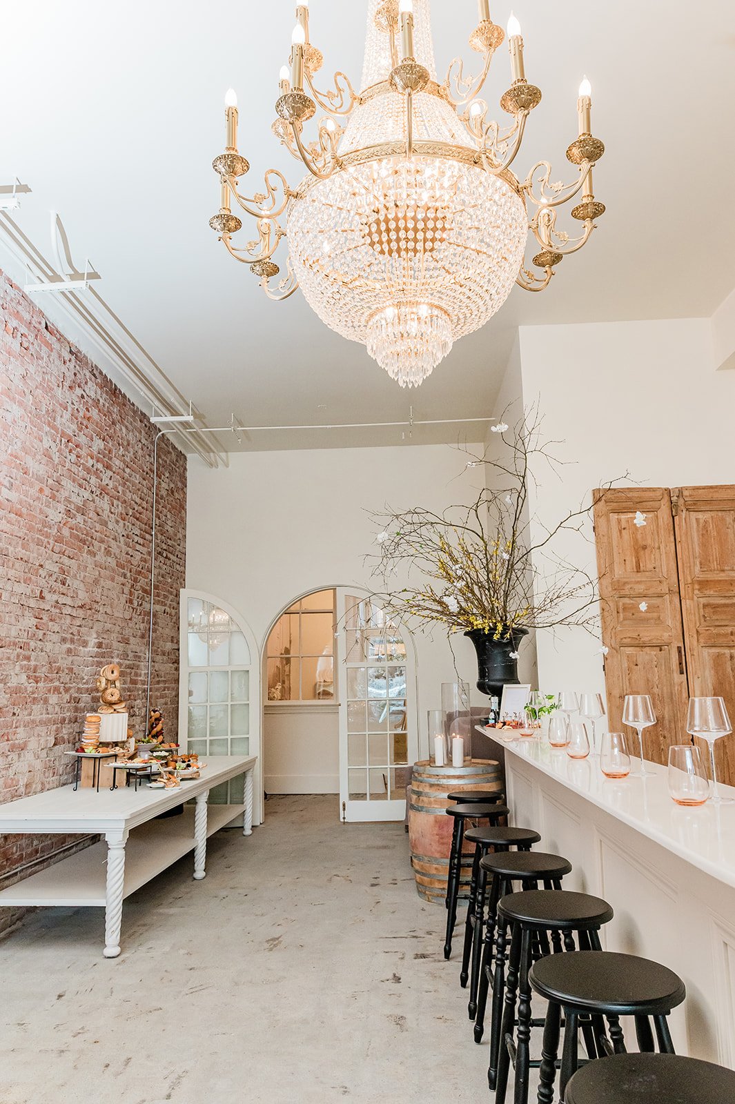 The Velvet & Oak interior — European chandelier, marble bar, arched doorways and original brick