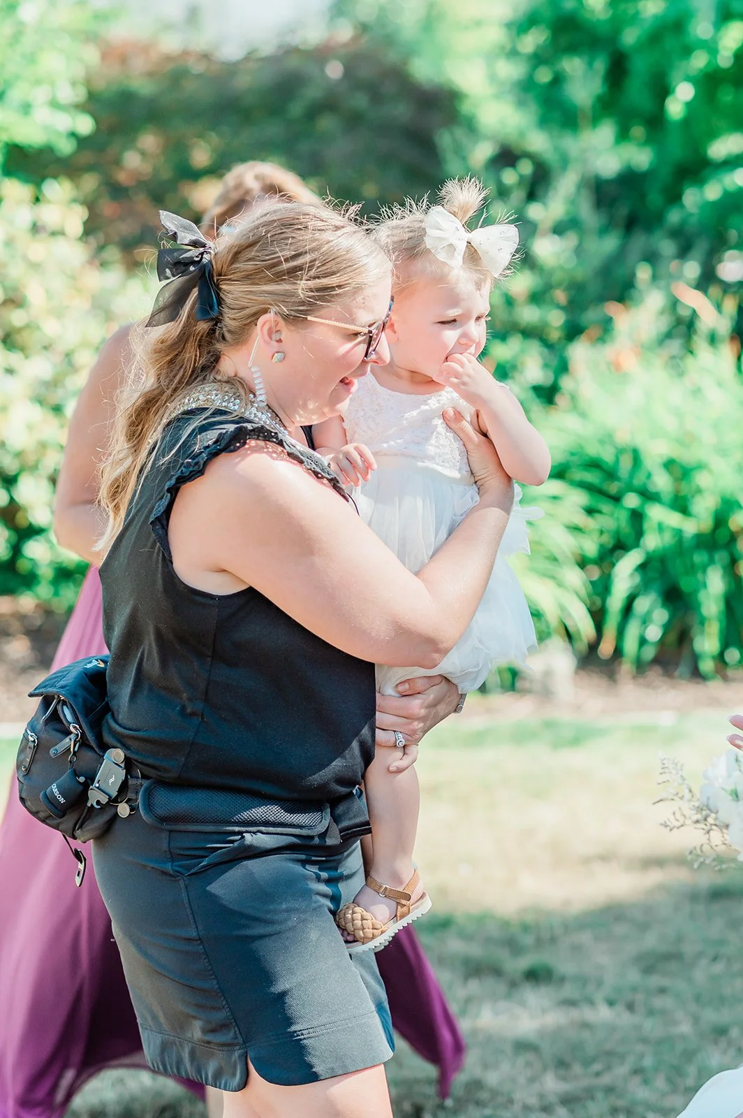 Snohomish wedding photographer Becca Jones holding the flower girl during bridal party photos at The Carey Gardens
