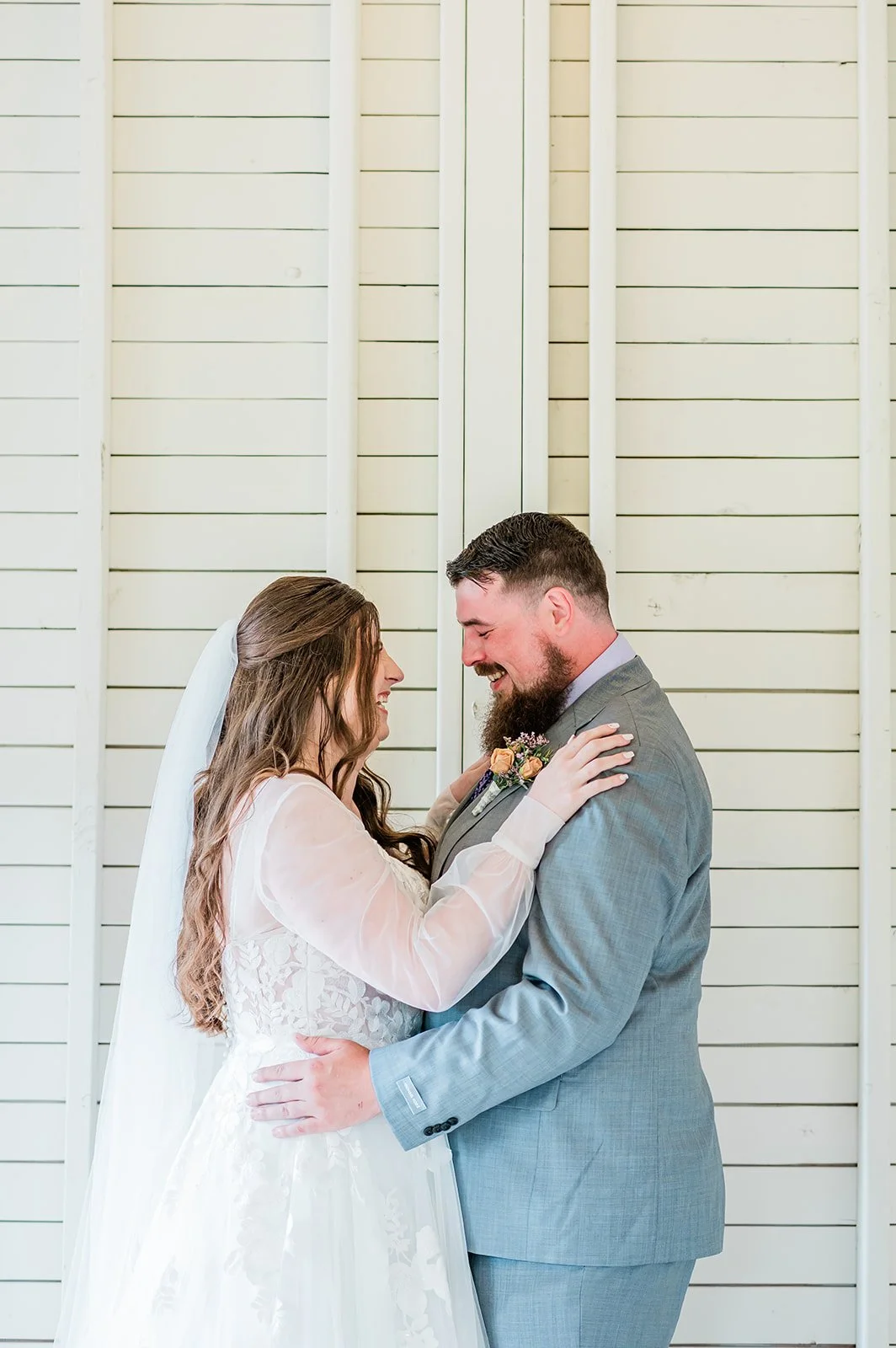 Meghan and Beau embracing during an emotional first look against white shiplap walls