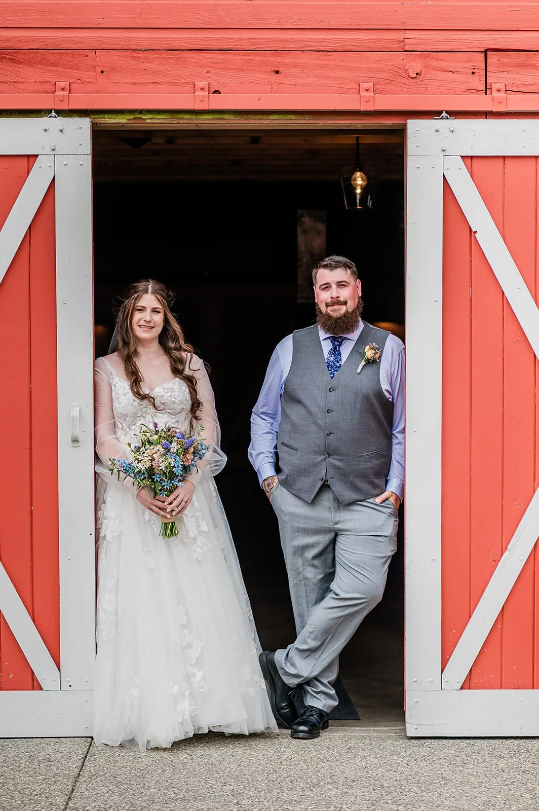 Bride and groom standing in the red and white barn doorway at Marionfield Farm