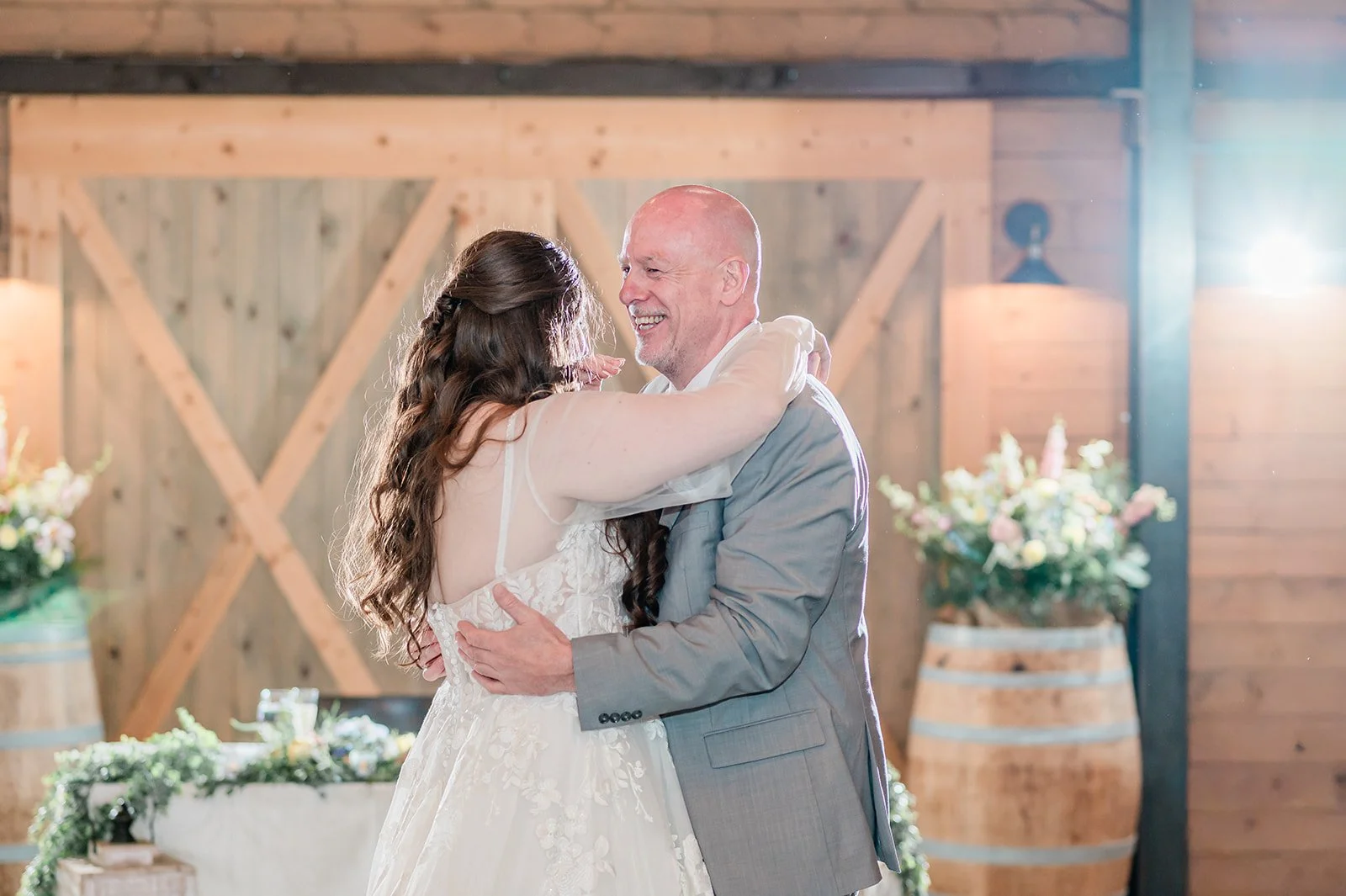 Bride dancing with her father in front of the barn doors at her Arlington farm wedding