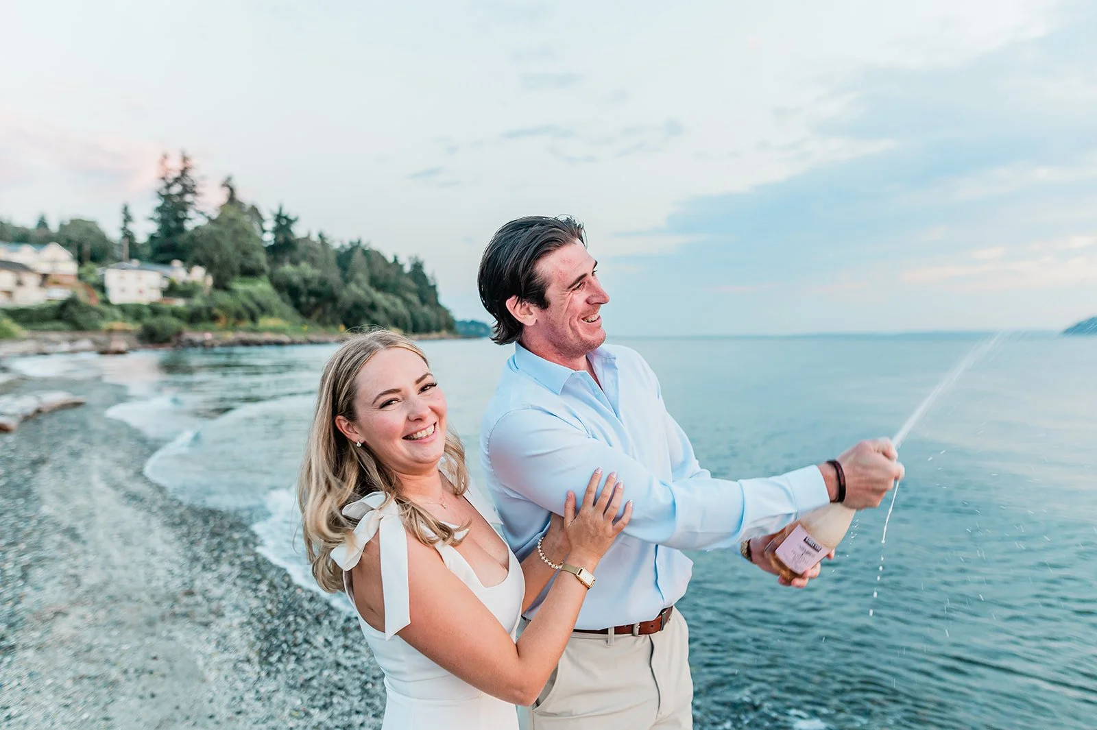 Couple popping champagne on the beach at their Mukilteo engagement session