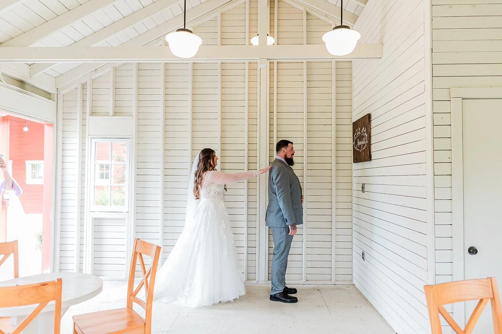 Bride approaching her groom for their first look inside the shiplap first look cottage at Marionfield Farm
