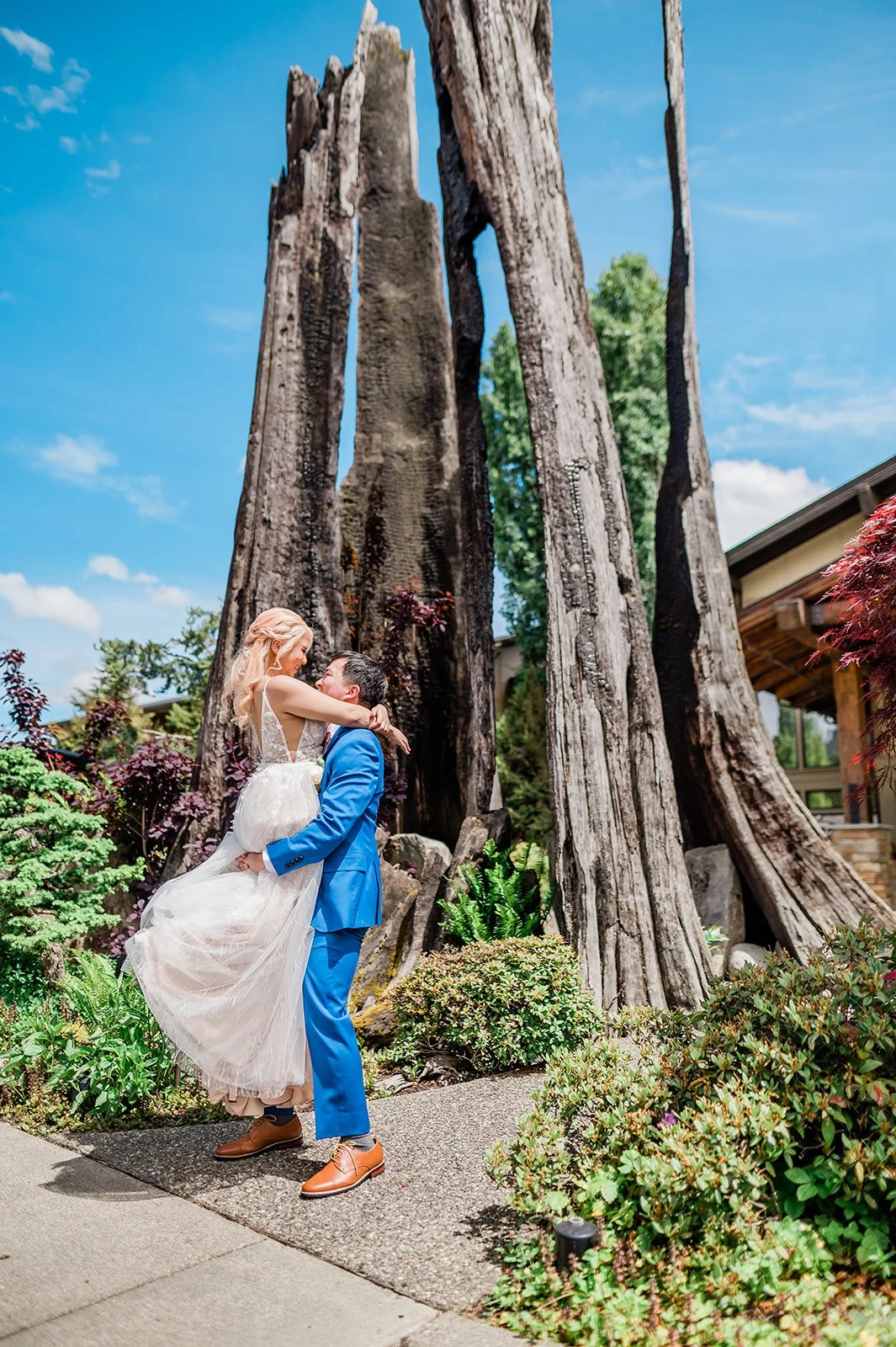 Groom lifting bride beside the burned-out tree trunk at Willows Lodge, Woodinville WA