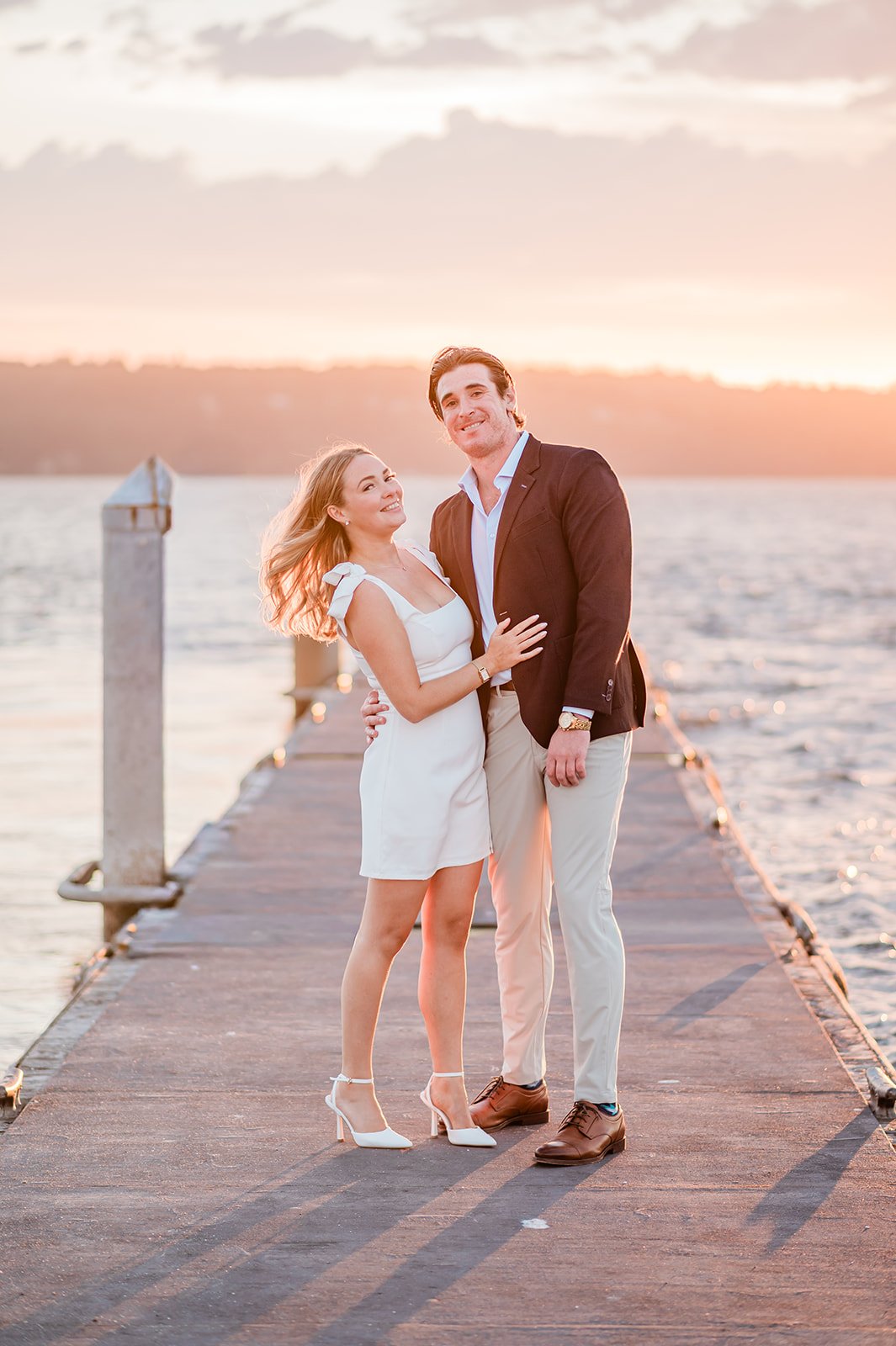 Engaged couple on the Mukilteo boat launch dock at sunset, pink sky over the water