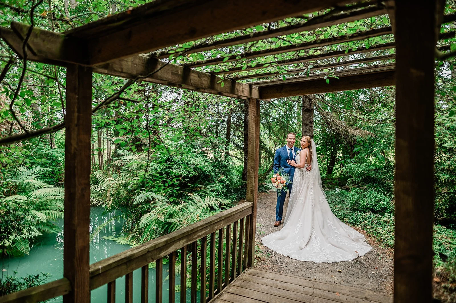 Couple embracing on the covered wooden deck over the pond, surrounded by forest