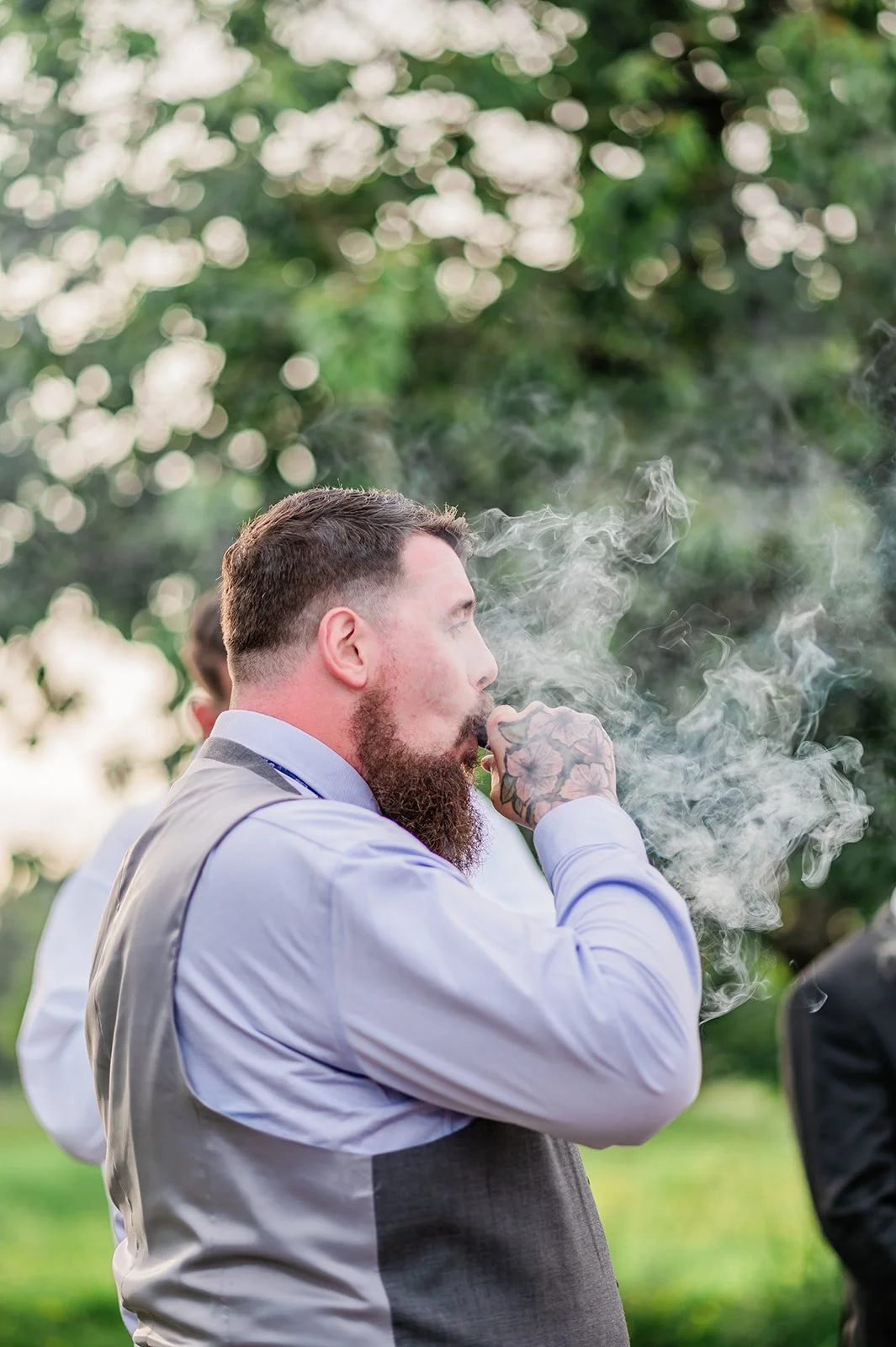 Groom enjoying a celebratory cigar outside during the reception