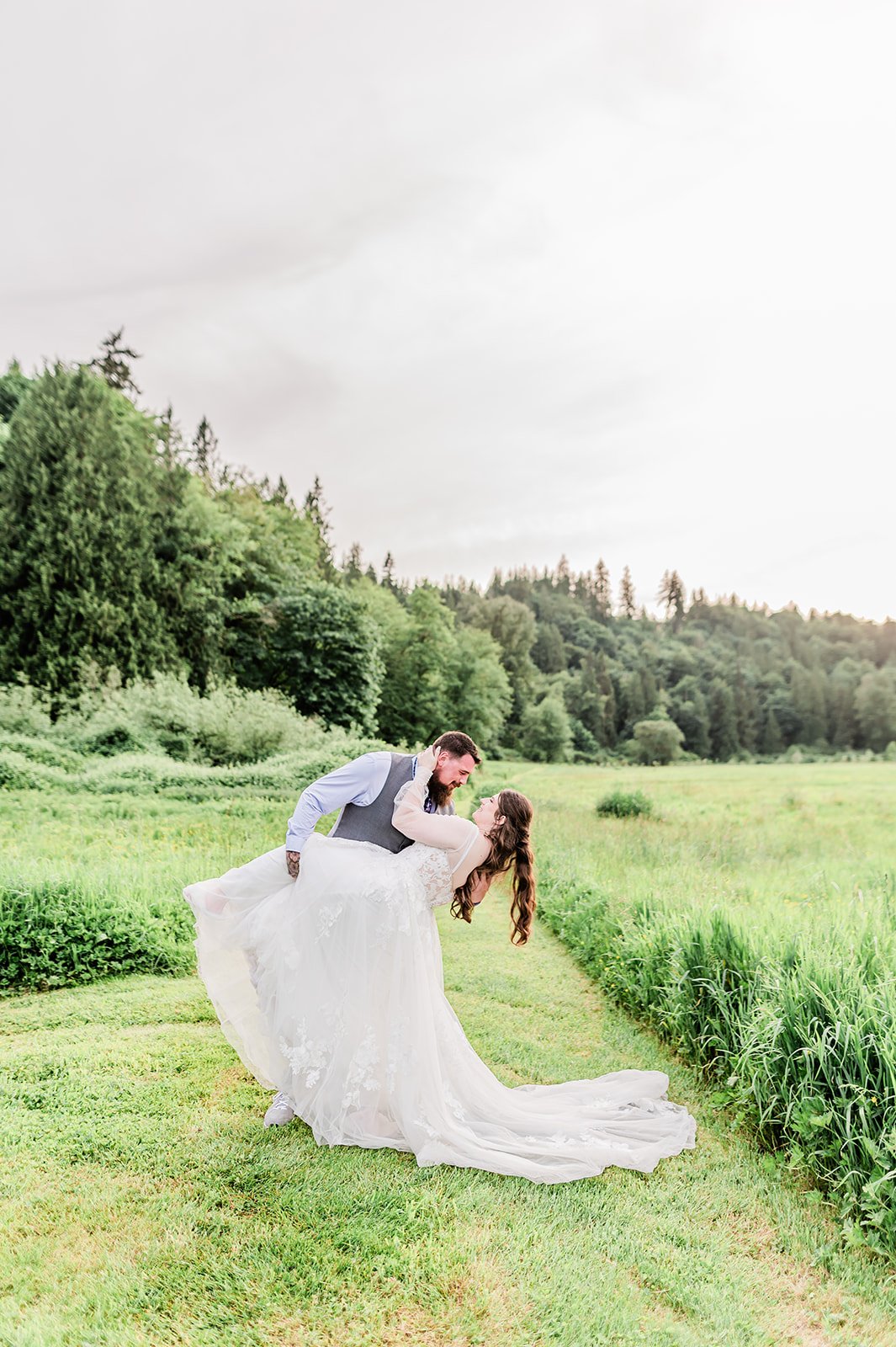 Groom dipping his bride in a green field at golden hour in Snohomish County