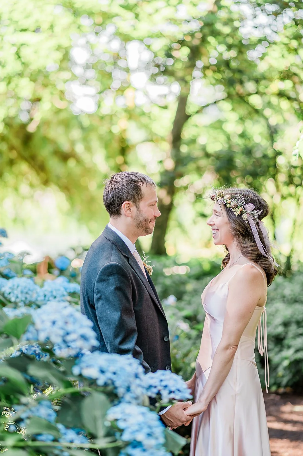 Bride and groom holding hands surrounded by blue hydrangeas at Seattle's Volunteer Park