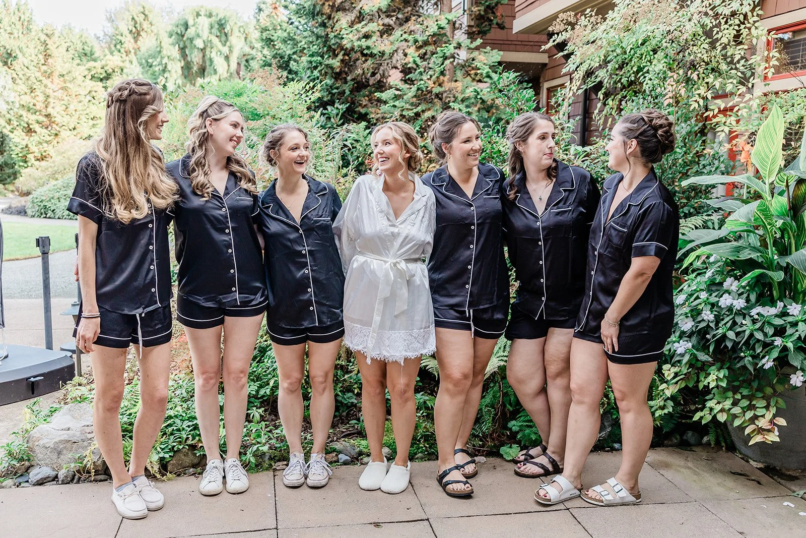Bridesmaids in matching black pajama sets laughing with the bride before getting dressed at Willows Lodge