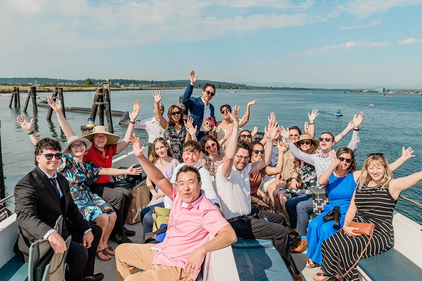 Wedding party celebrating with hands raised on the Jetty Island ferry during a micro wedding in Everett Washington